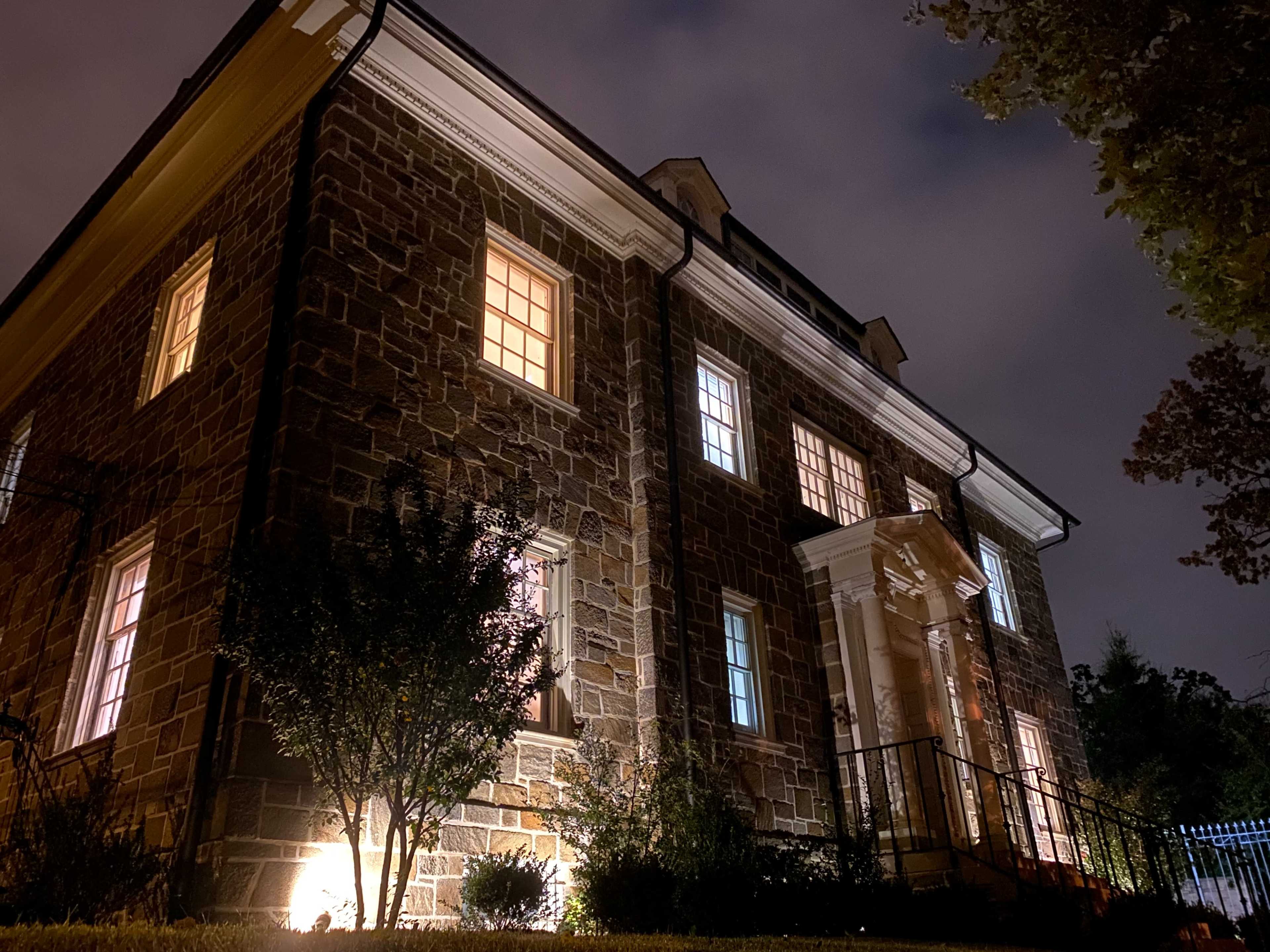 A stone building with illuminated windows is set against a night sky.