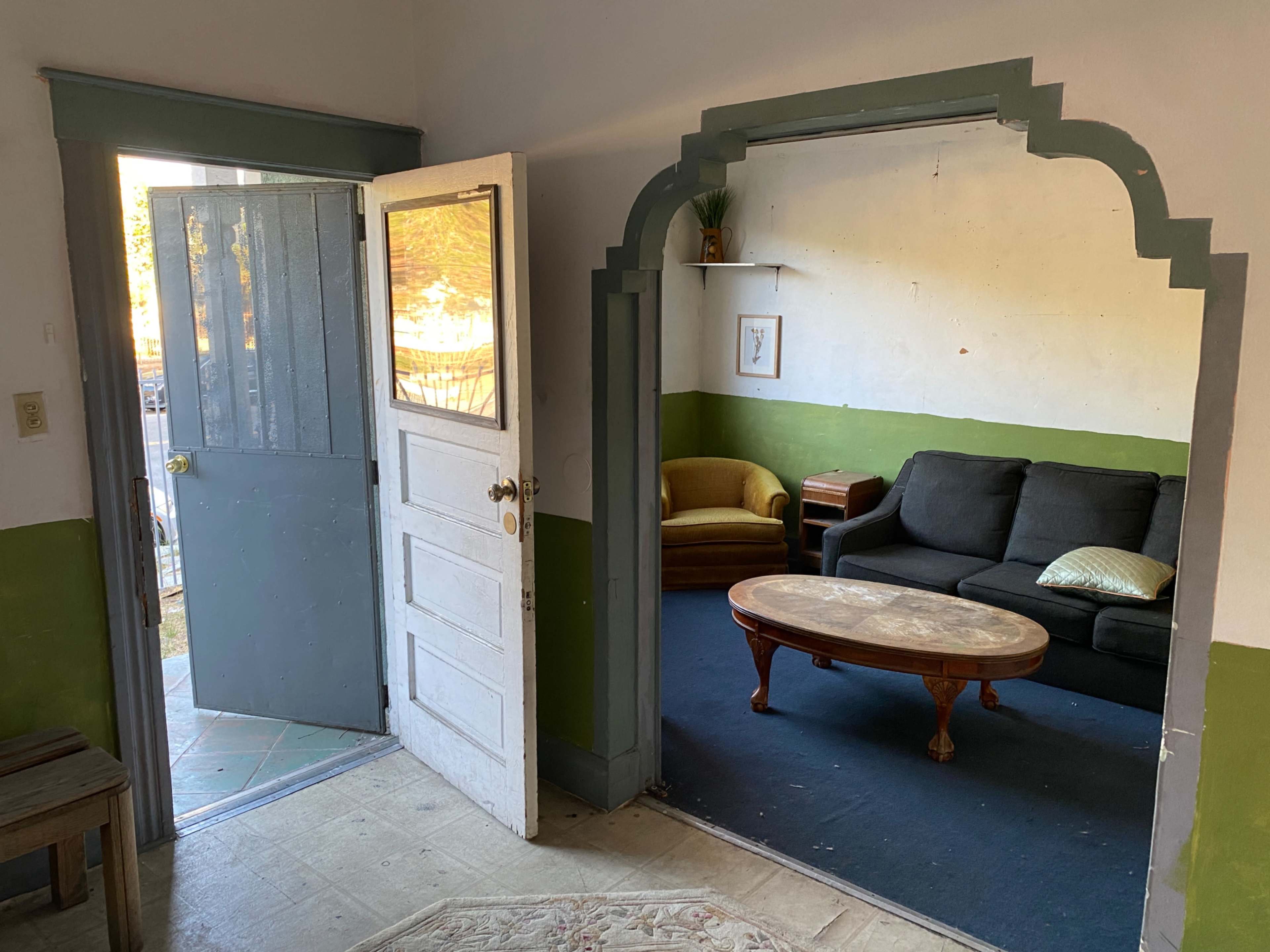 An open doorway leading from a hallway into a small room furnished with a couch and a coffee table.