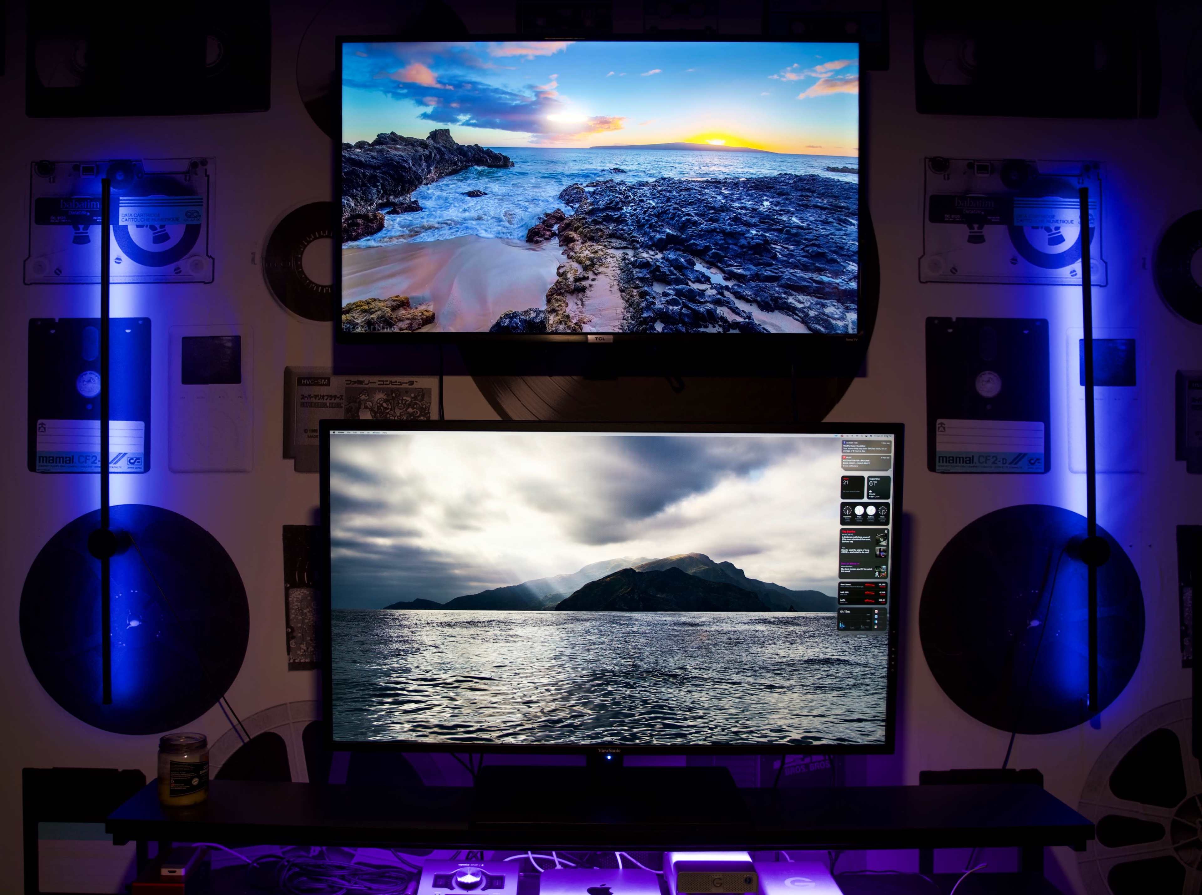 Two wall-mounted televisions displaying landscape scenes, with colorful lighting and vinyl records adorning the background.