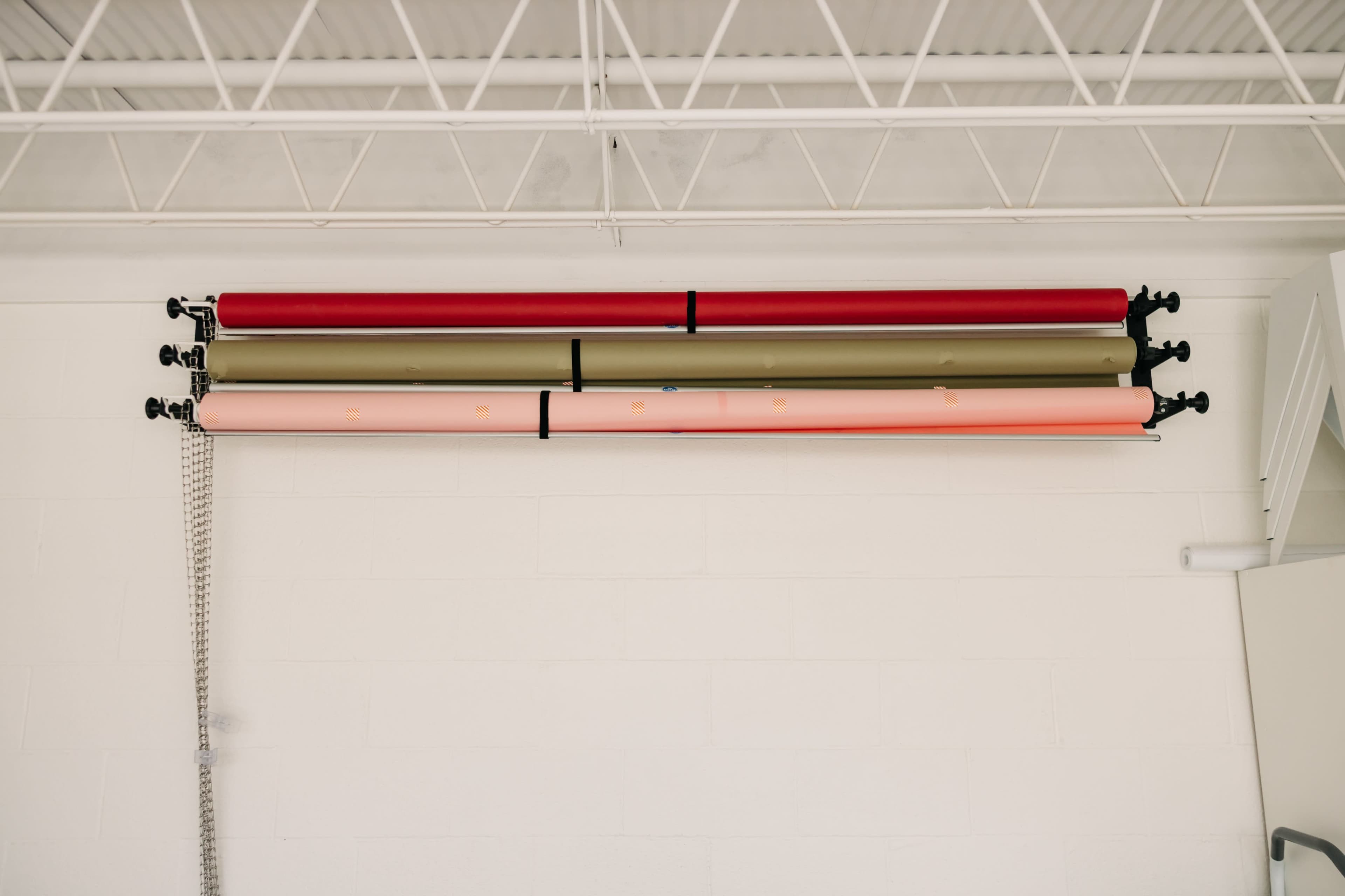 Rolls of colored paper are stored on a wall-mounted rack in a studio.