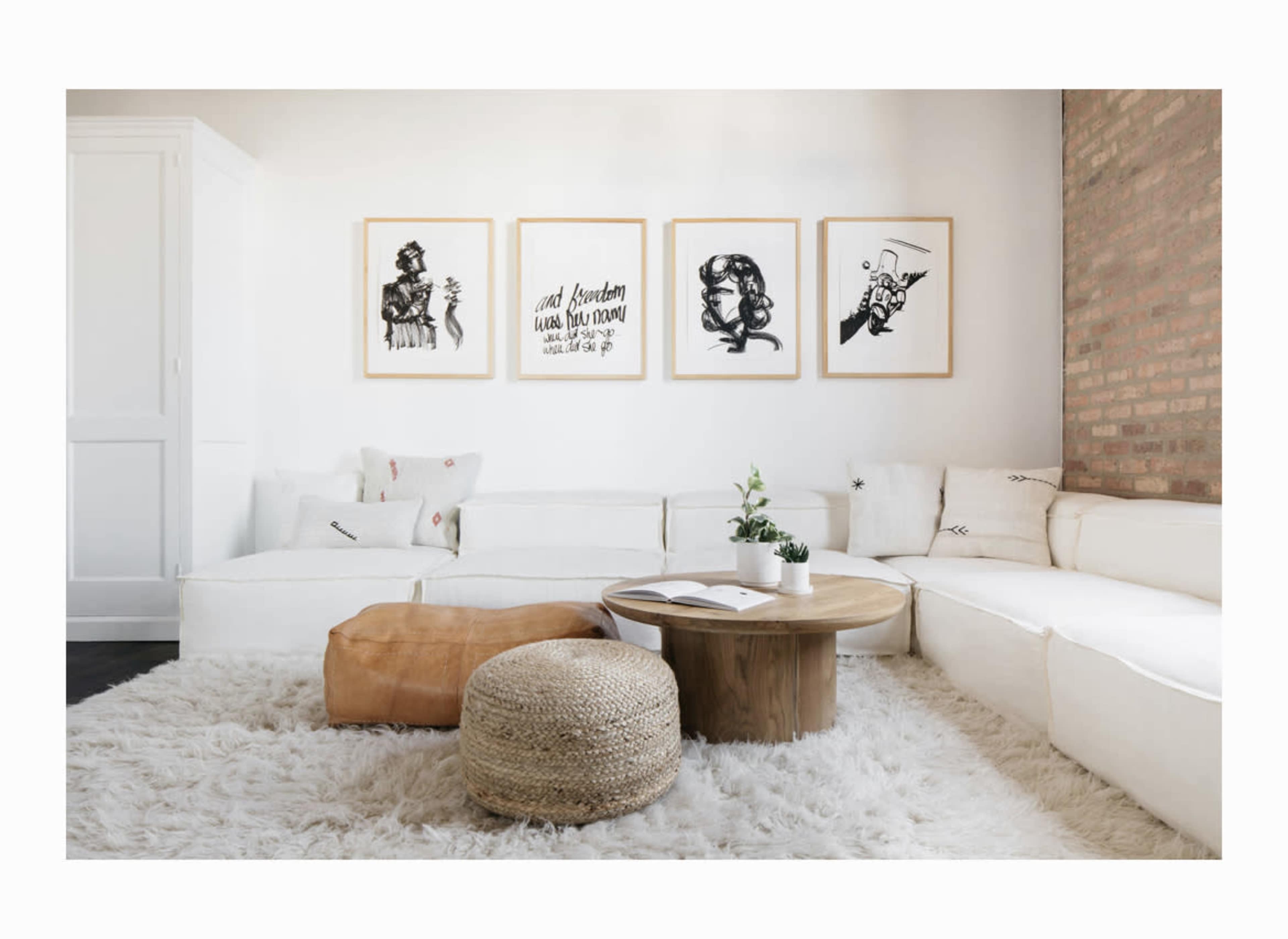 A modern living room featuring a white sectional sofa, a round wooden coffee table, and framed art on the wall, with a cozy rug underfoot.