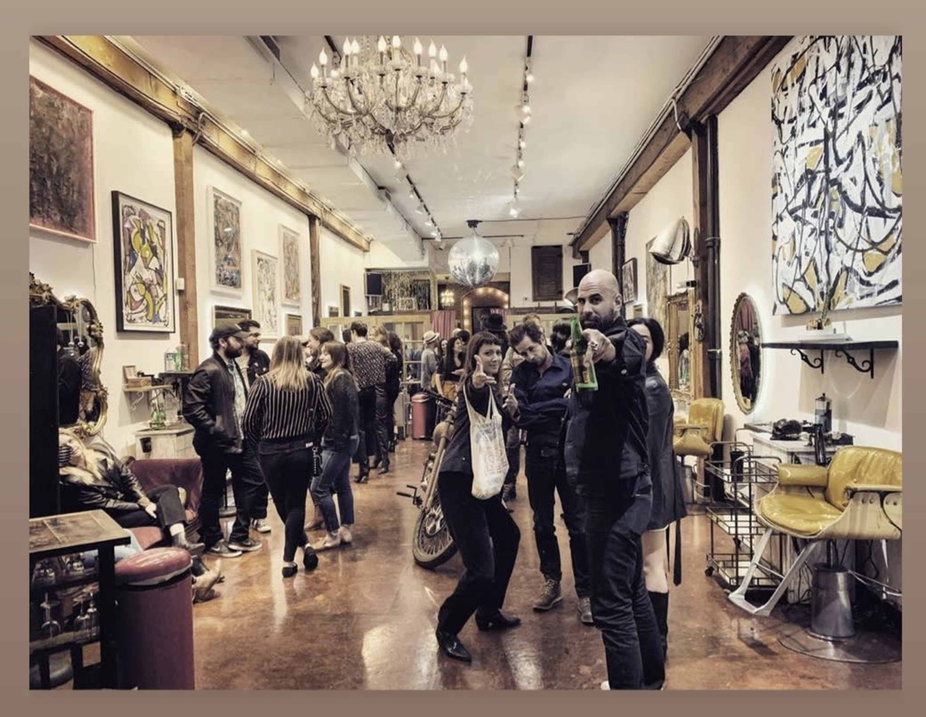 A lively art gallery features people socializing and interacting amidst various artworks and furnishings.