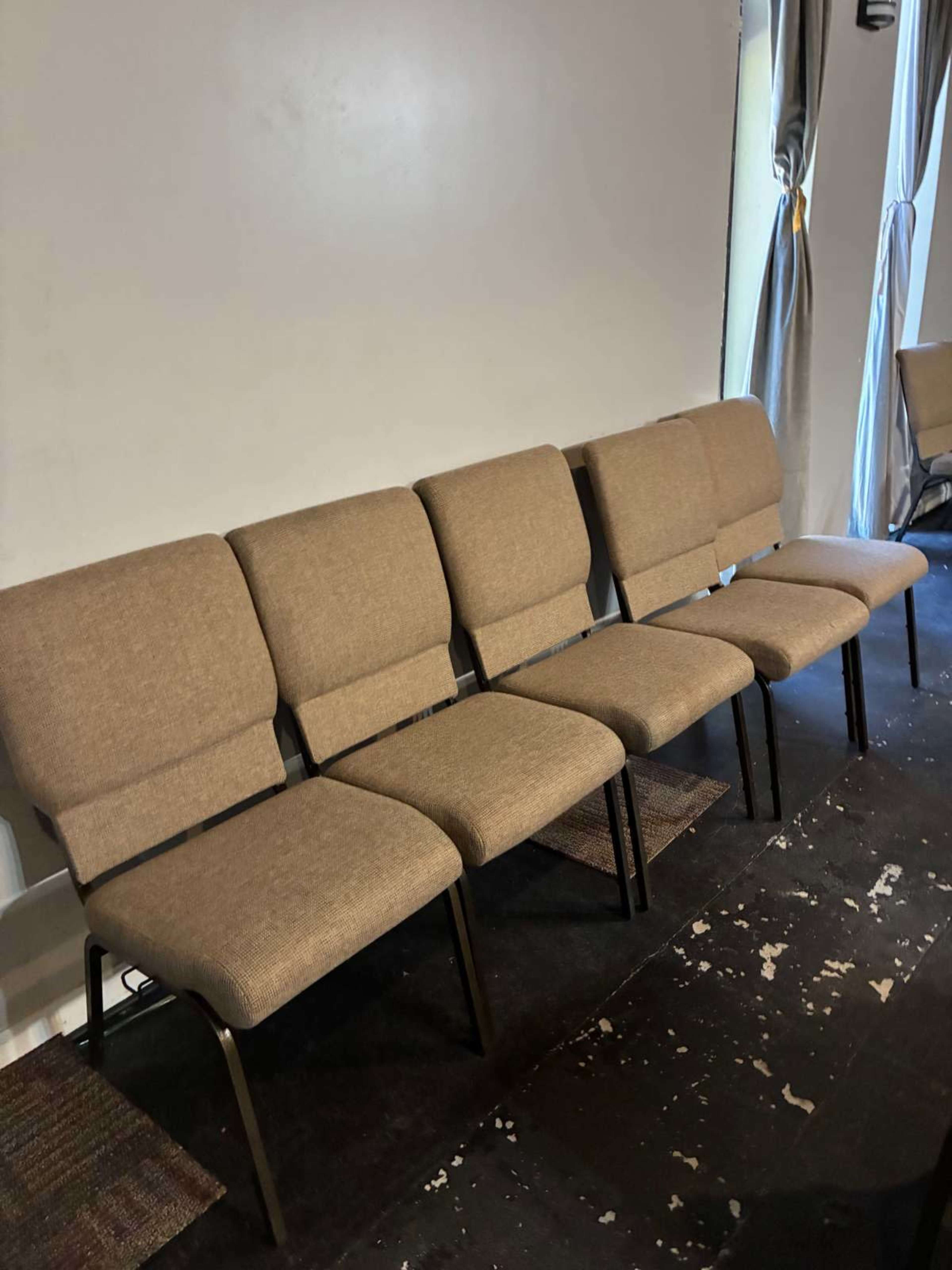 The image shows a row of five armless upholstered chairs arranged against a plain wall.