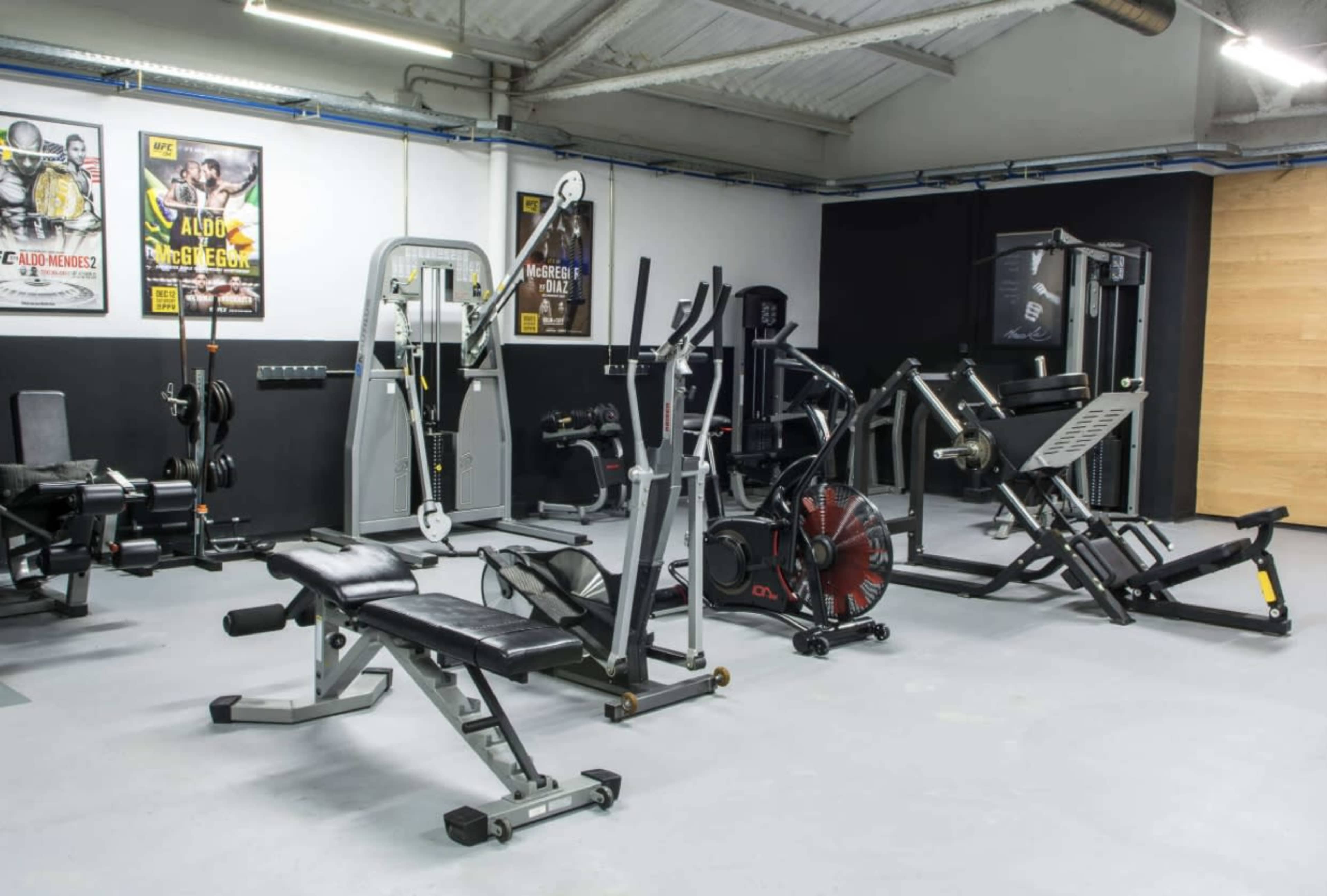A well-equipped gym with various weight machines, benches, and exercise equipment arranged in a spacious interior.
