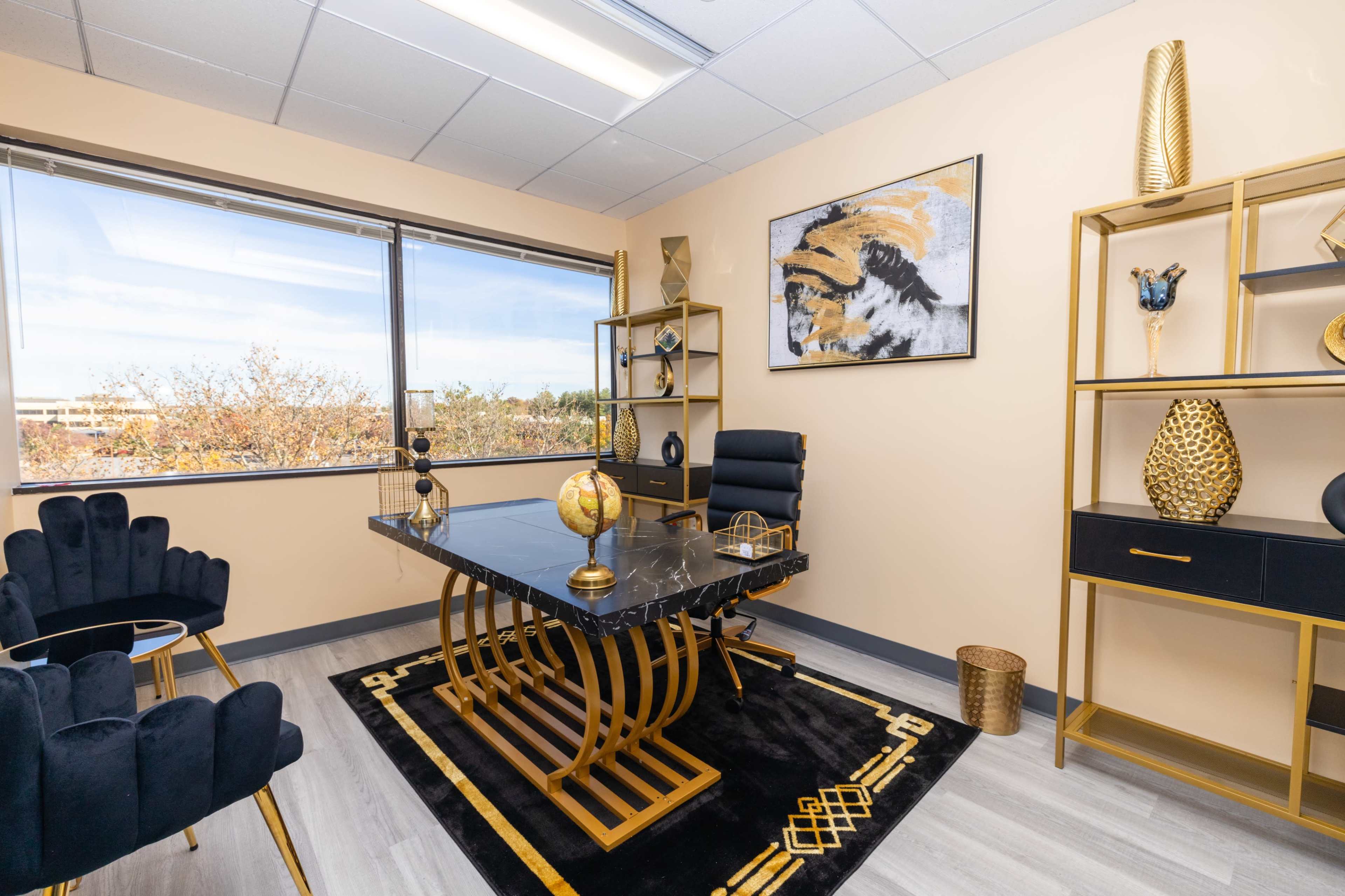 A modern office space featuring a black marble desk, gold accents, and a large window that allows natural light to enter.