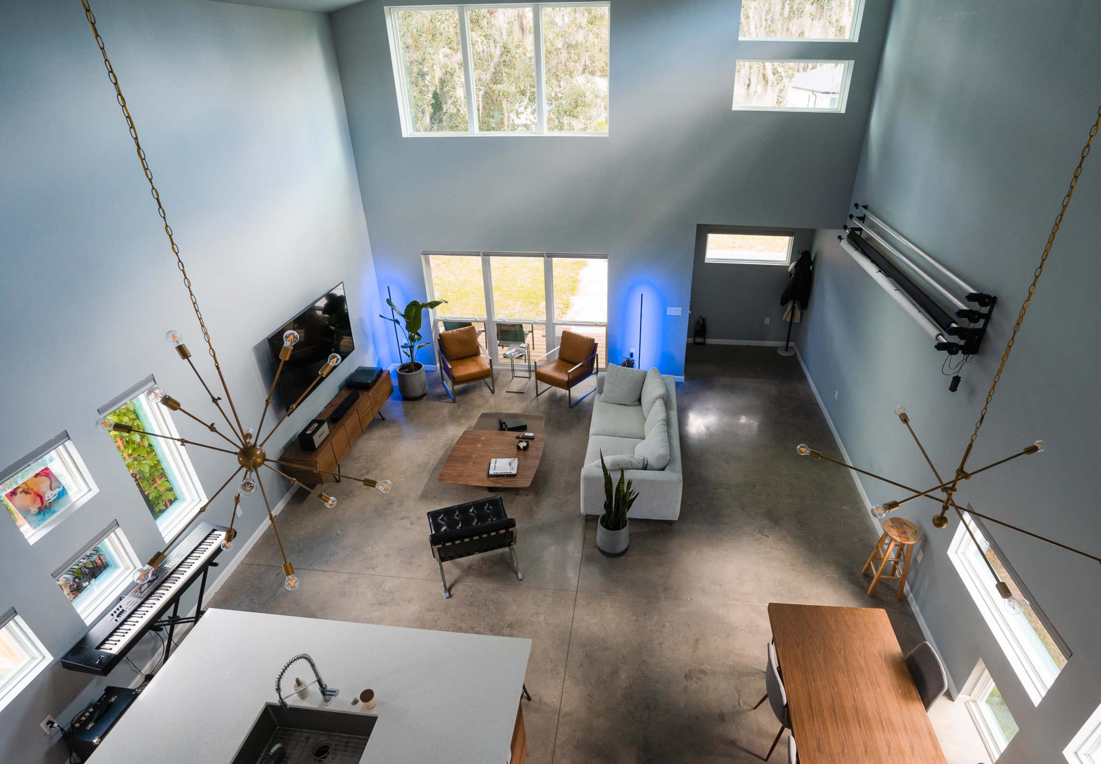 A spacious, modern living area featuring a sectional sofa, dining table, and large windows that provide natural light.