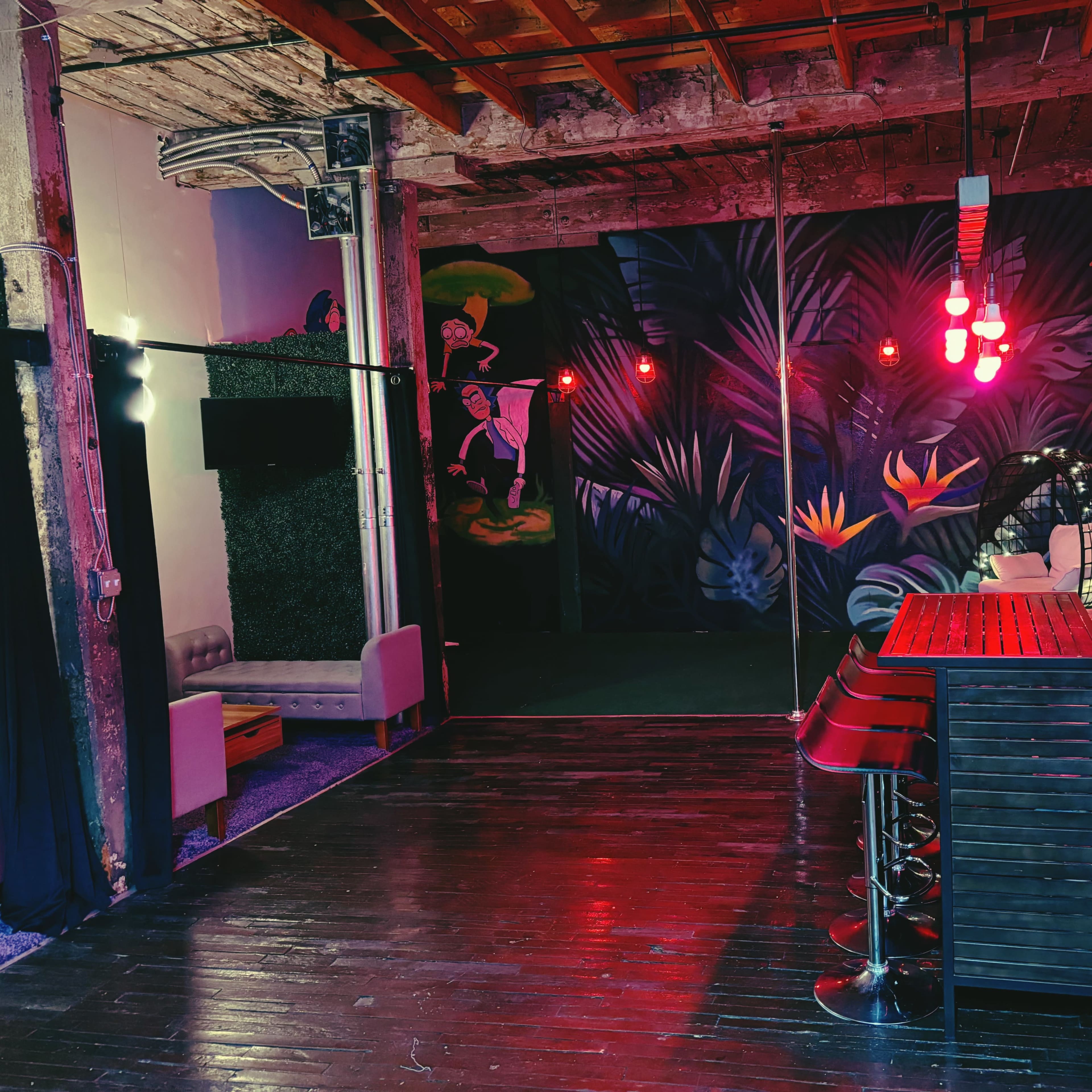 A decorated lounge area with a bar, red pendant lights, and a vibrant mural on one wall.