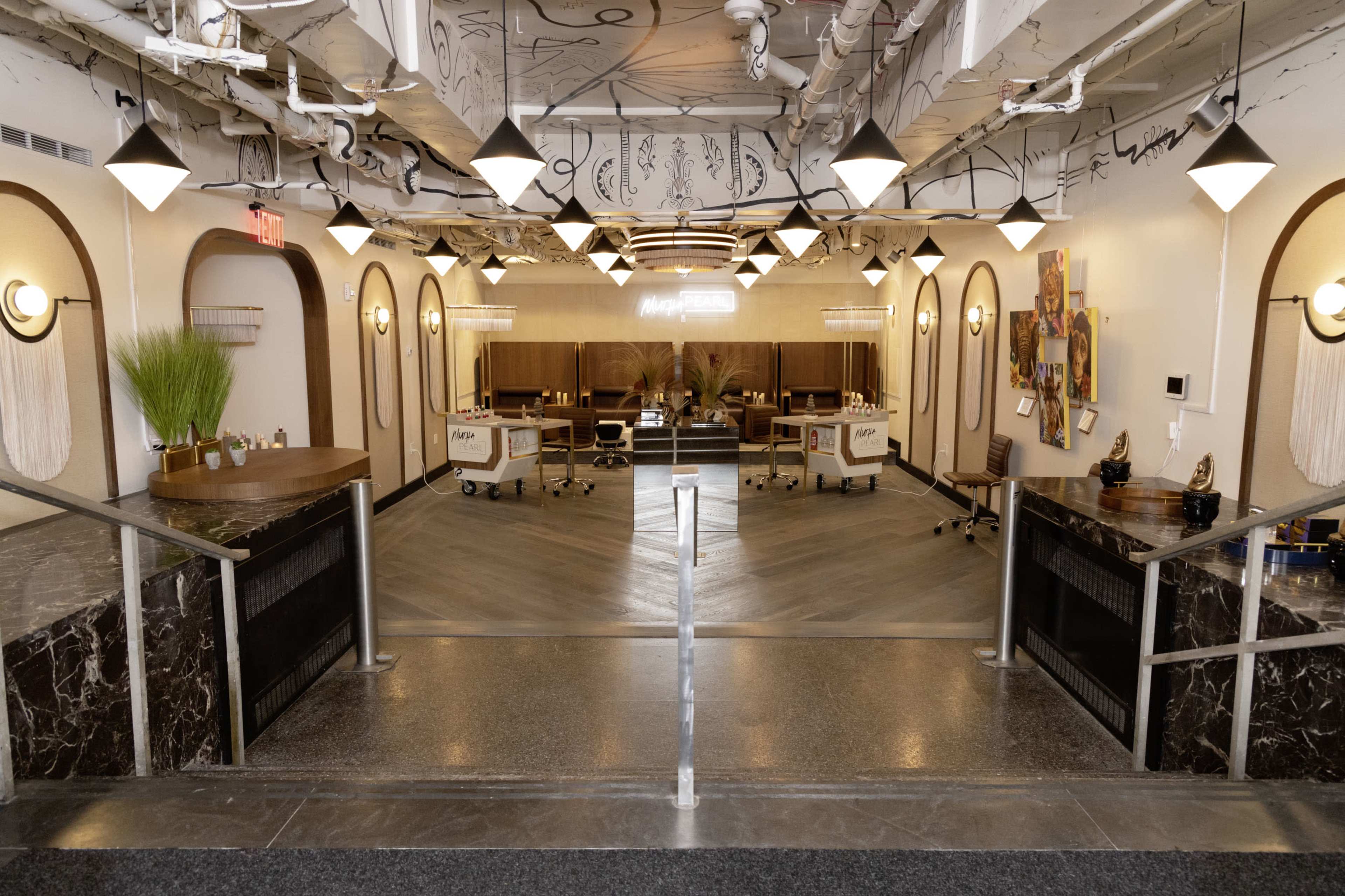 A modern salon interior featuring workstations with chairs, elegant lighting fixtures, and a decorative layout.