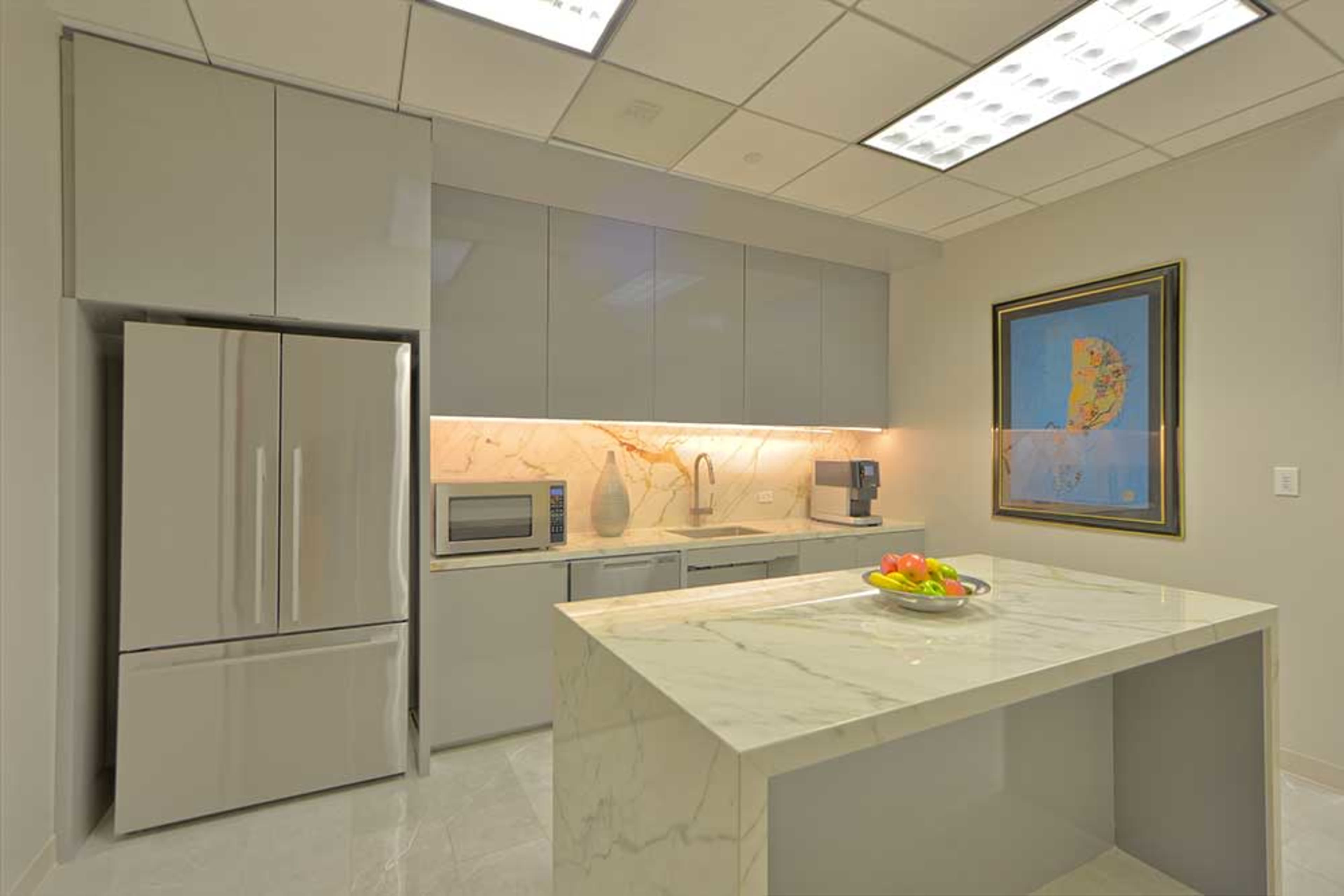 The image shows a modern kitchen featuring gray cabinets, a marble countertop, and stainless steel appliances, including a refrigerator and microwave.
