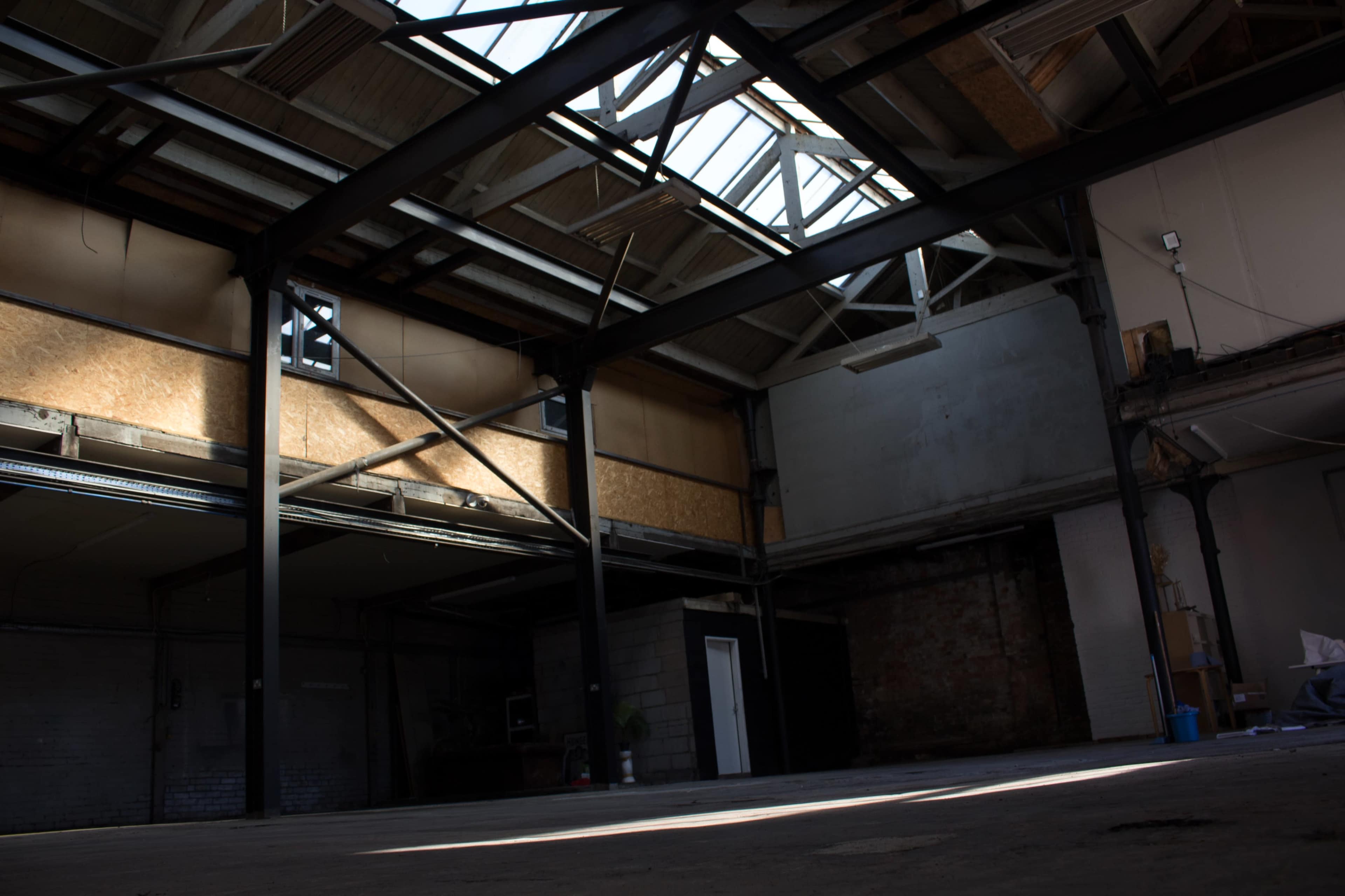 An empty industrial warehouse with large windows and metal beams.