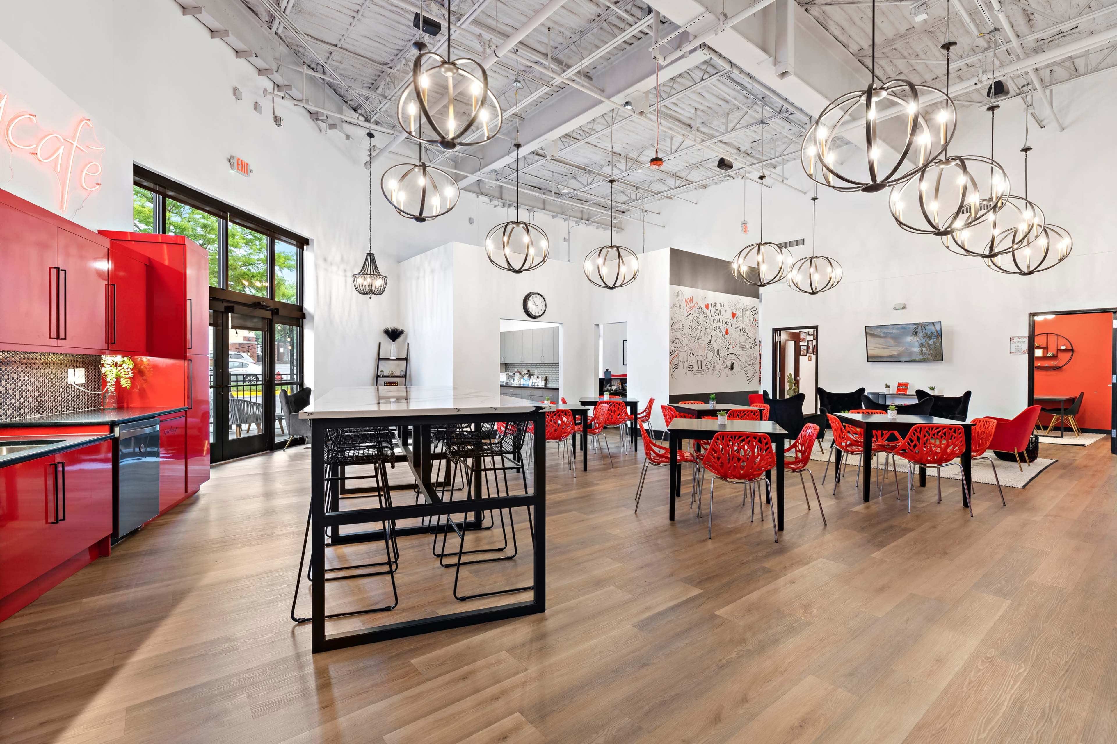A modern cafe interior with red cabinets, circular pendant lights, and a mix of red and black dining chairs.