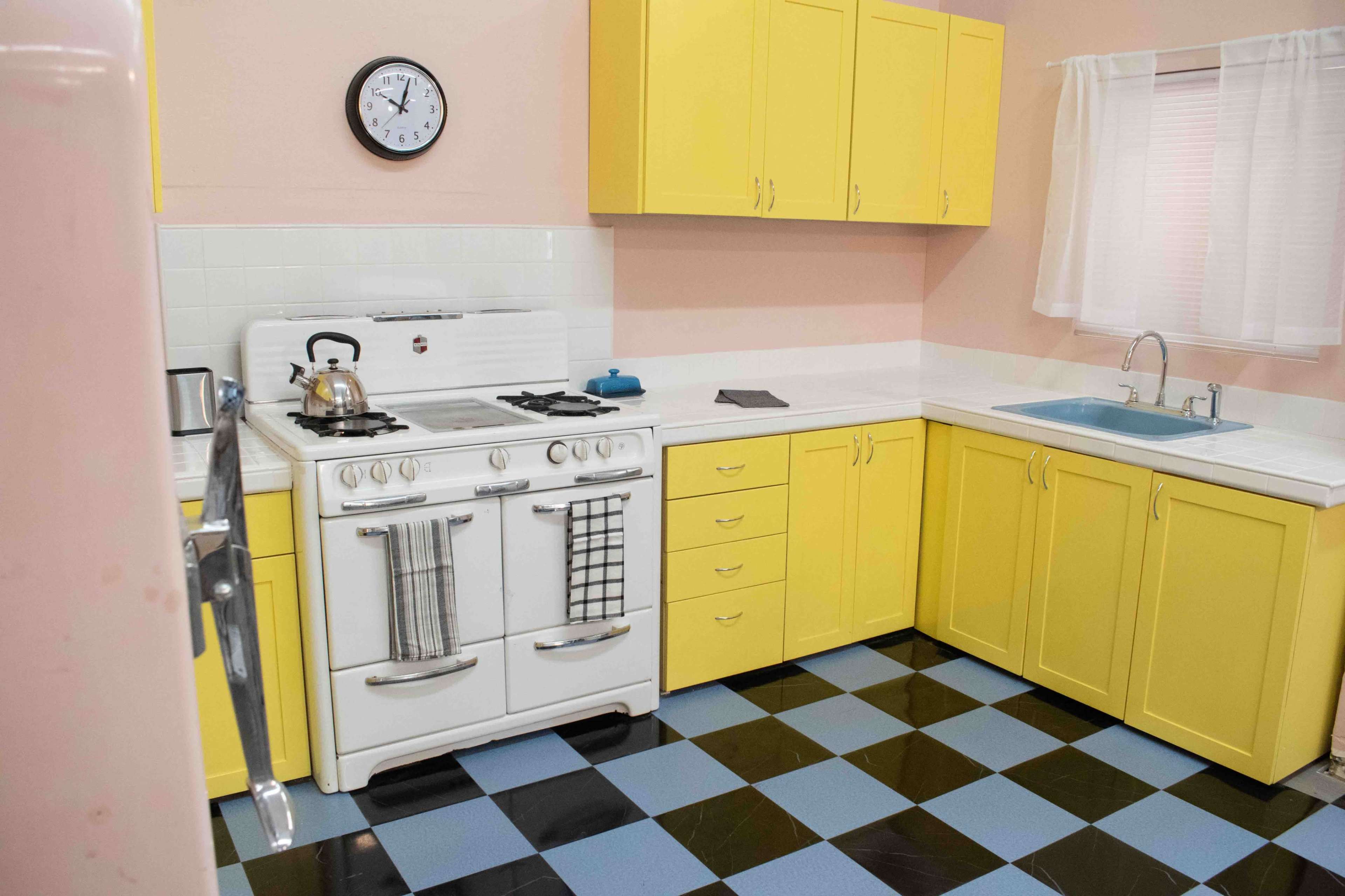 The kitchen features yellow cabinetry, a white stove, and a blue and black checkered floor.