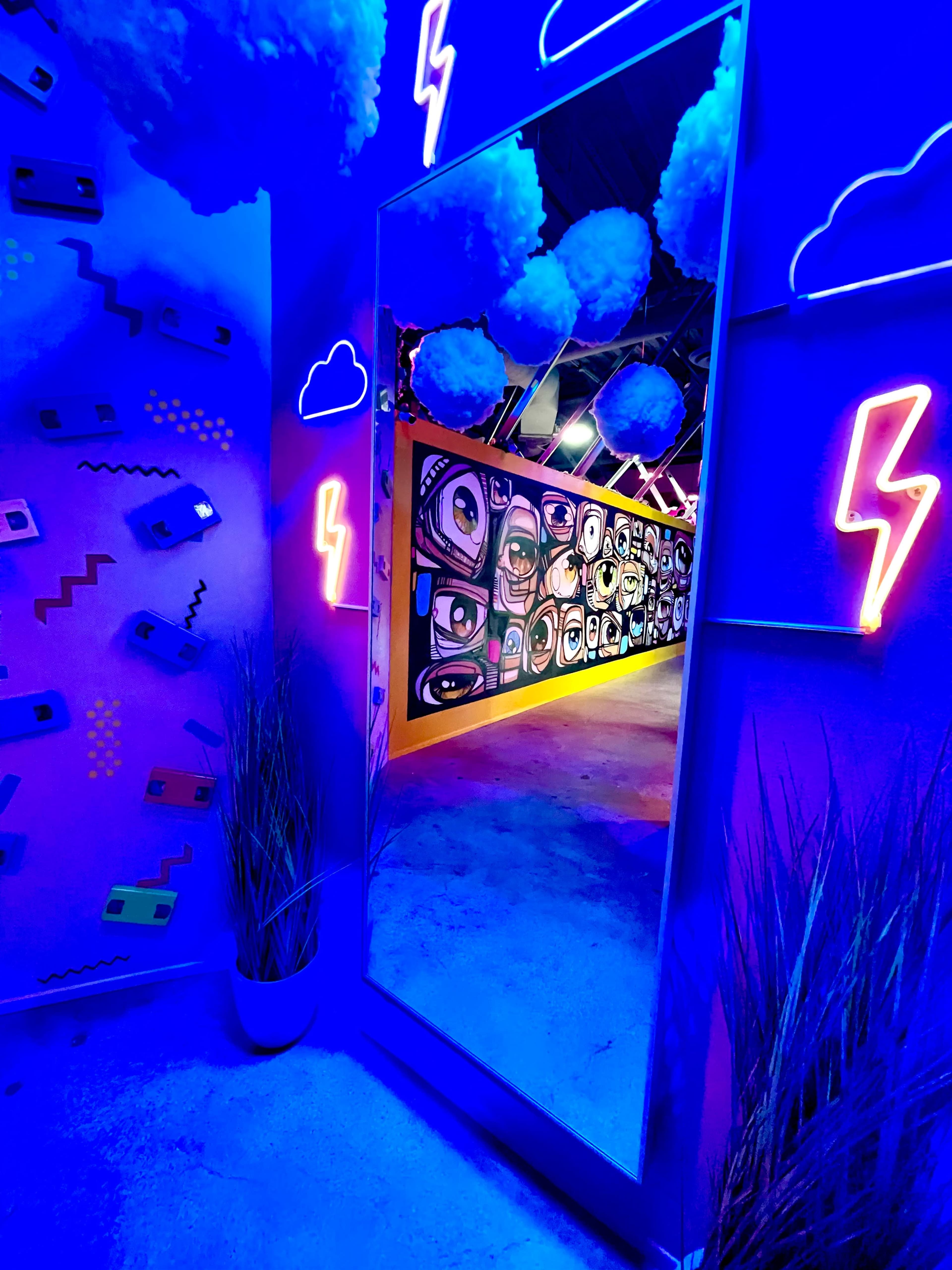 A brightly lit corridor featuring colorful wall art, a large mirror, and decorative elements with clouds and lightning motifs.