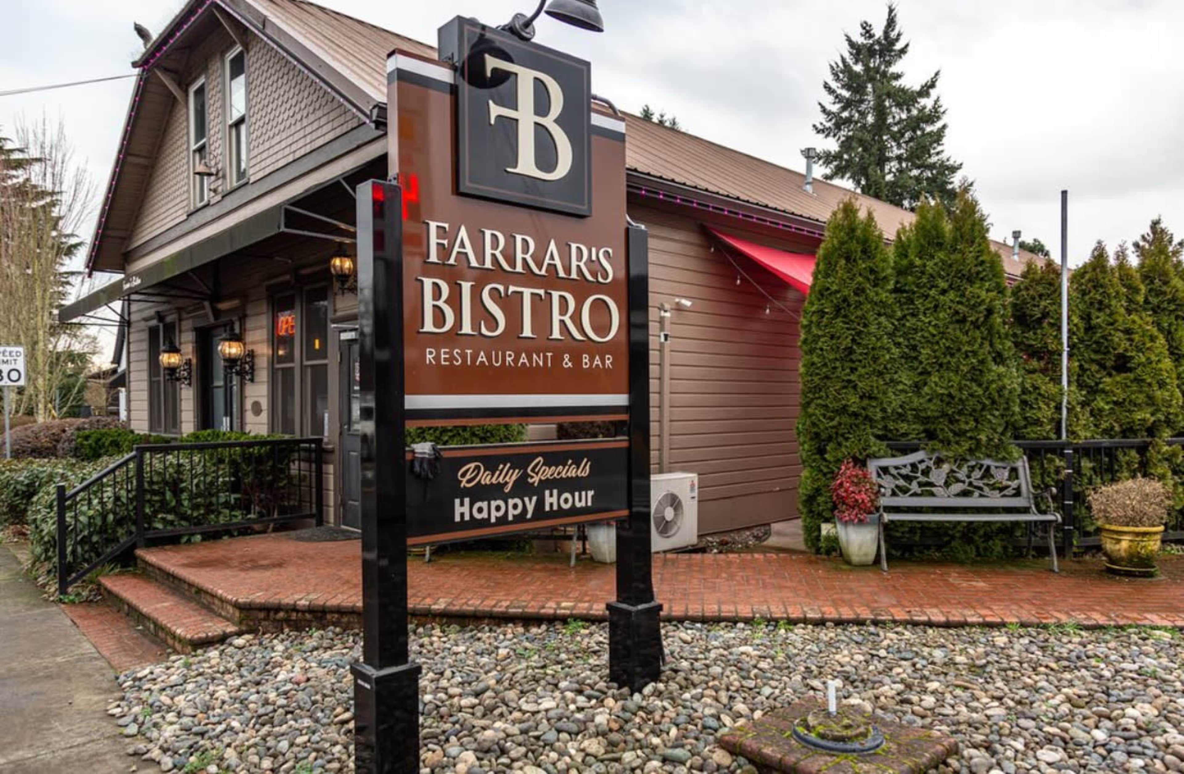 The image shows a sign for Farrar's Bistro, a restaurant and bar, situated in front of a building with a landscaped entrance and stone pathway.