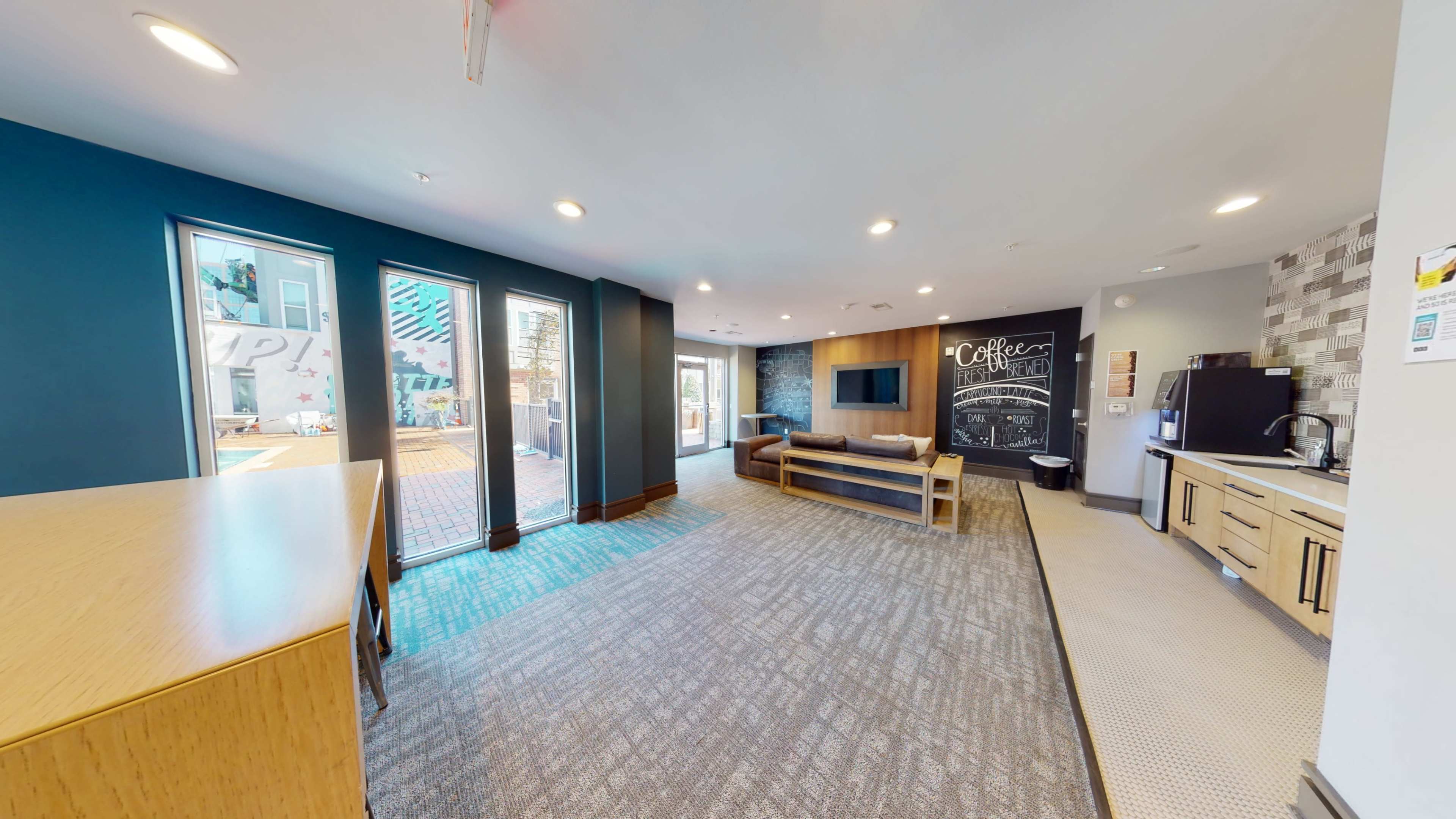 A modern communal space with a seating area, kitchenette, and a large chalkboard wall.
