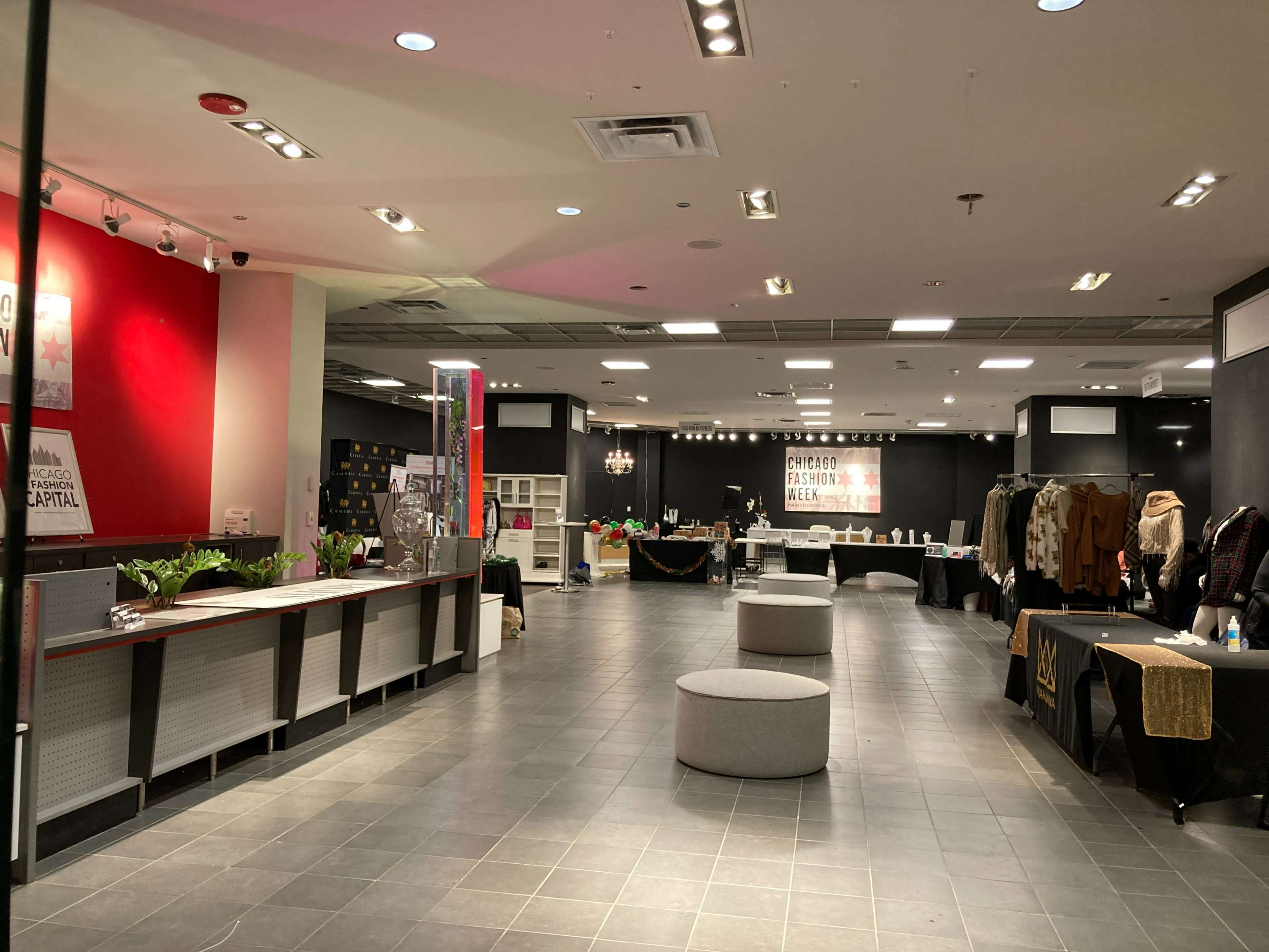 The image shows a spacious retail store interior with a reception area on the left and various clothing displays and tables set up in the background.