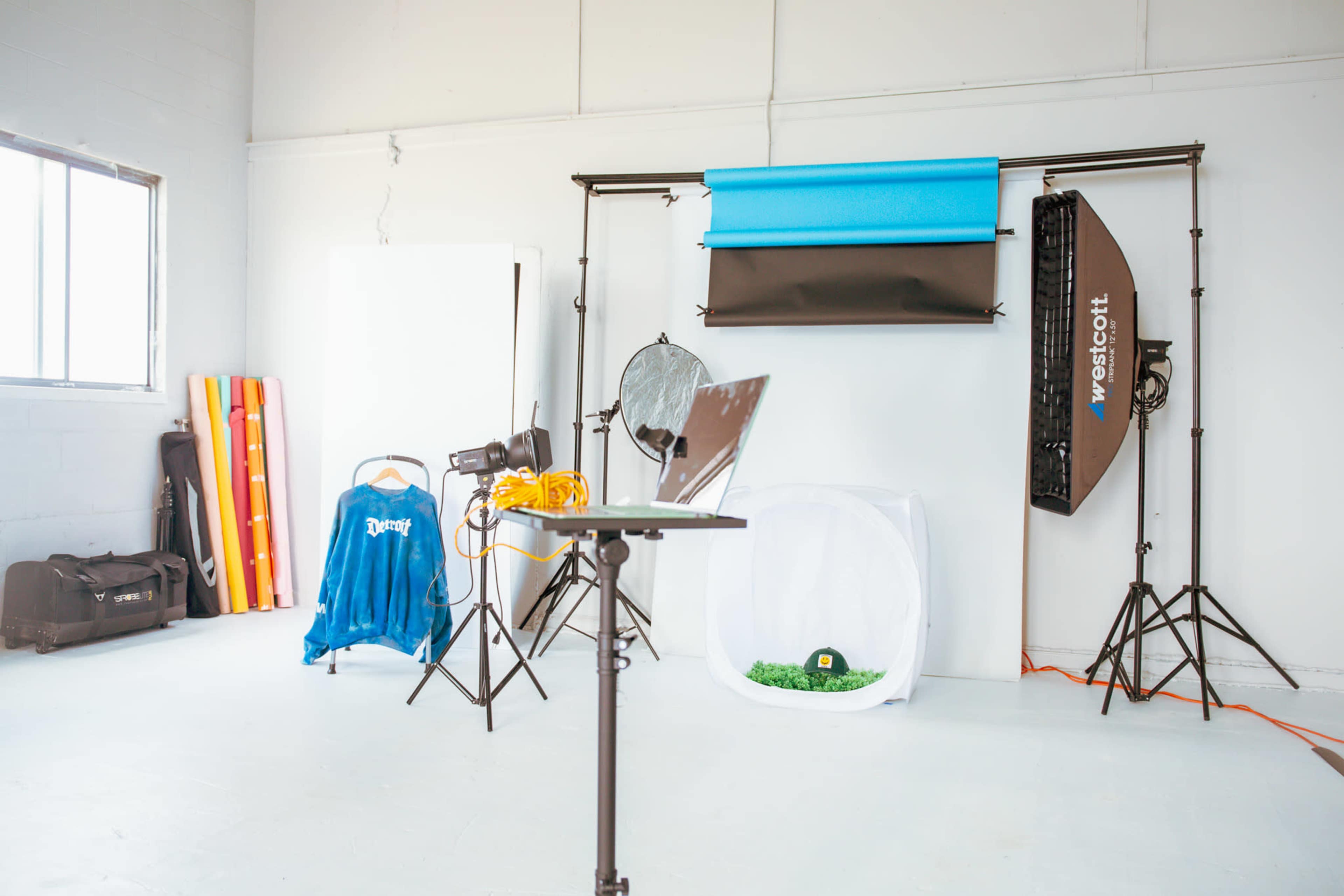 A photography studio setup is shown, featuring backdrops, lighting equipment, a table, and various props.
