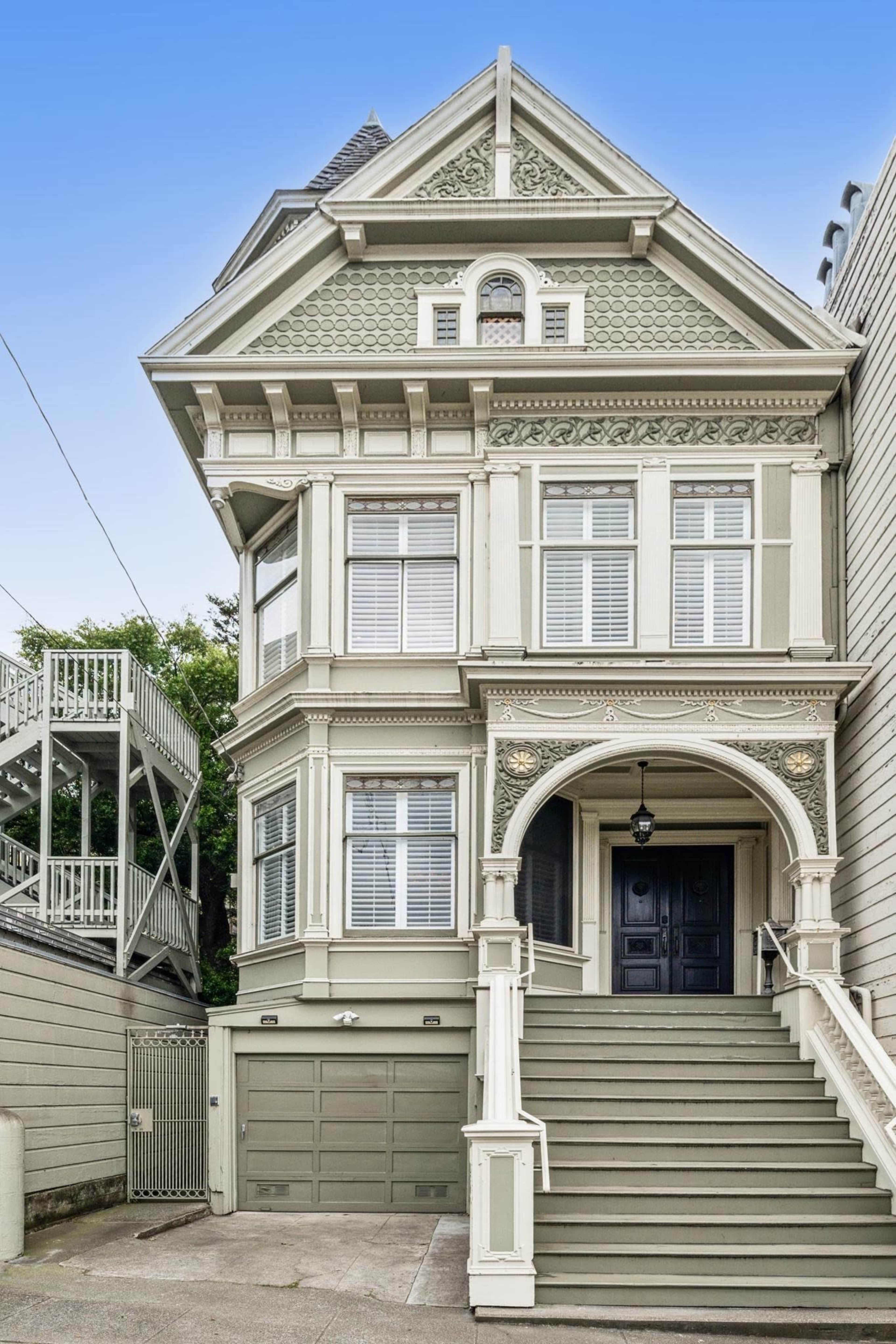 A large Victorian-style house with intricate architectural details and a grand staircase leading to the front door.