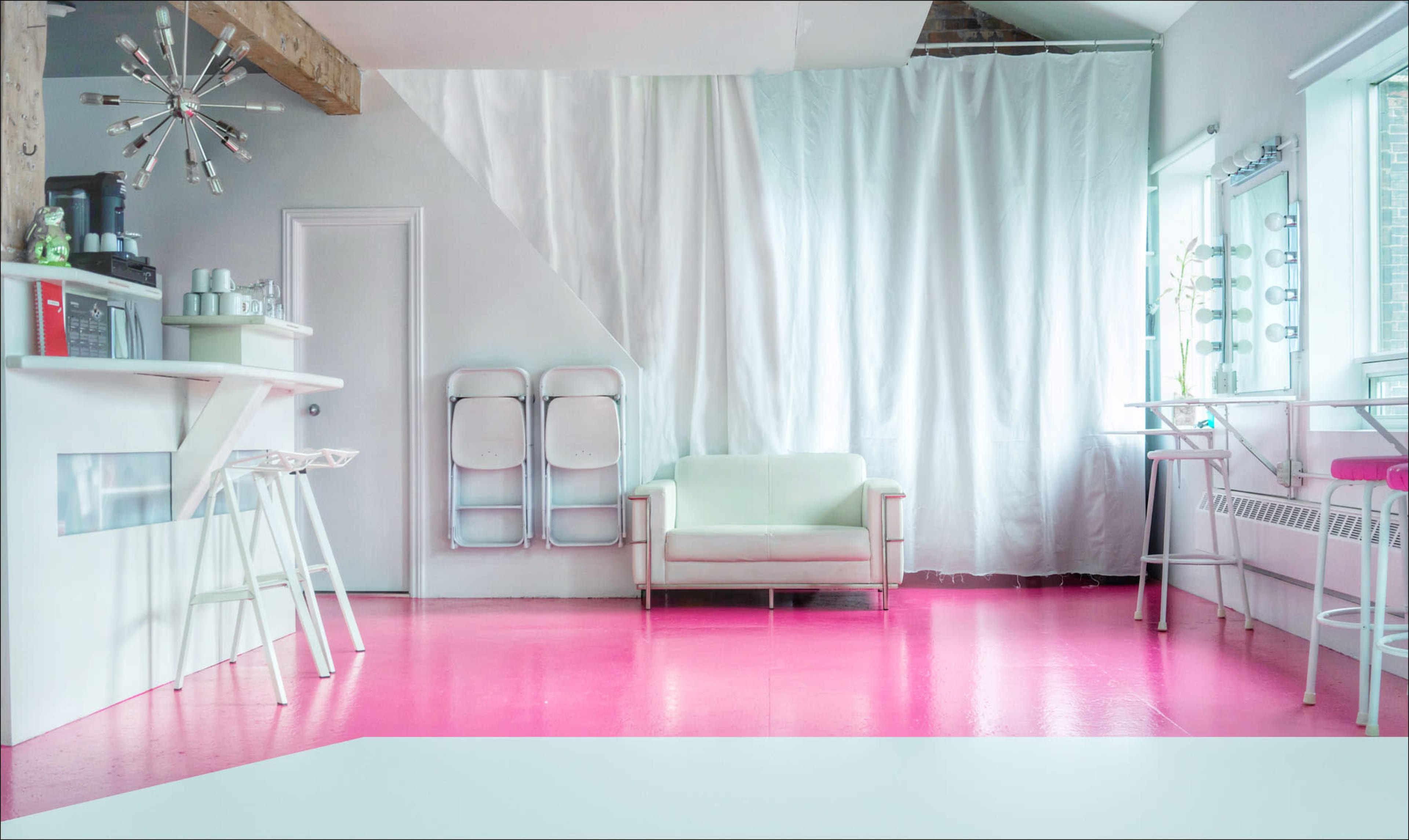 A modern room with pink flooring, a light green couch, and a bar area with stools.