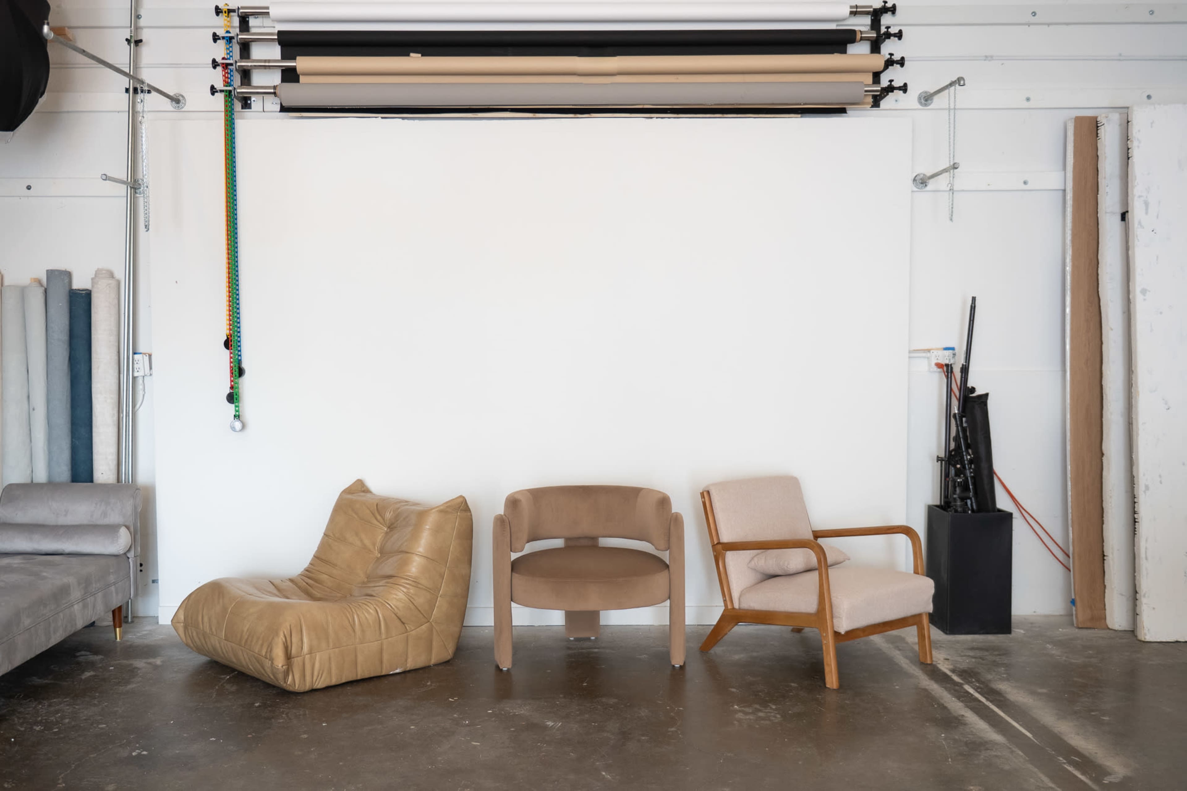 The image shows three different style chairs positioned against a plain white wall in a studio-like setting.