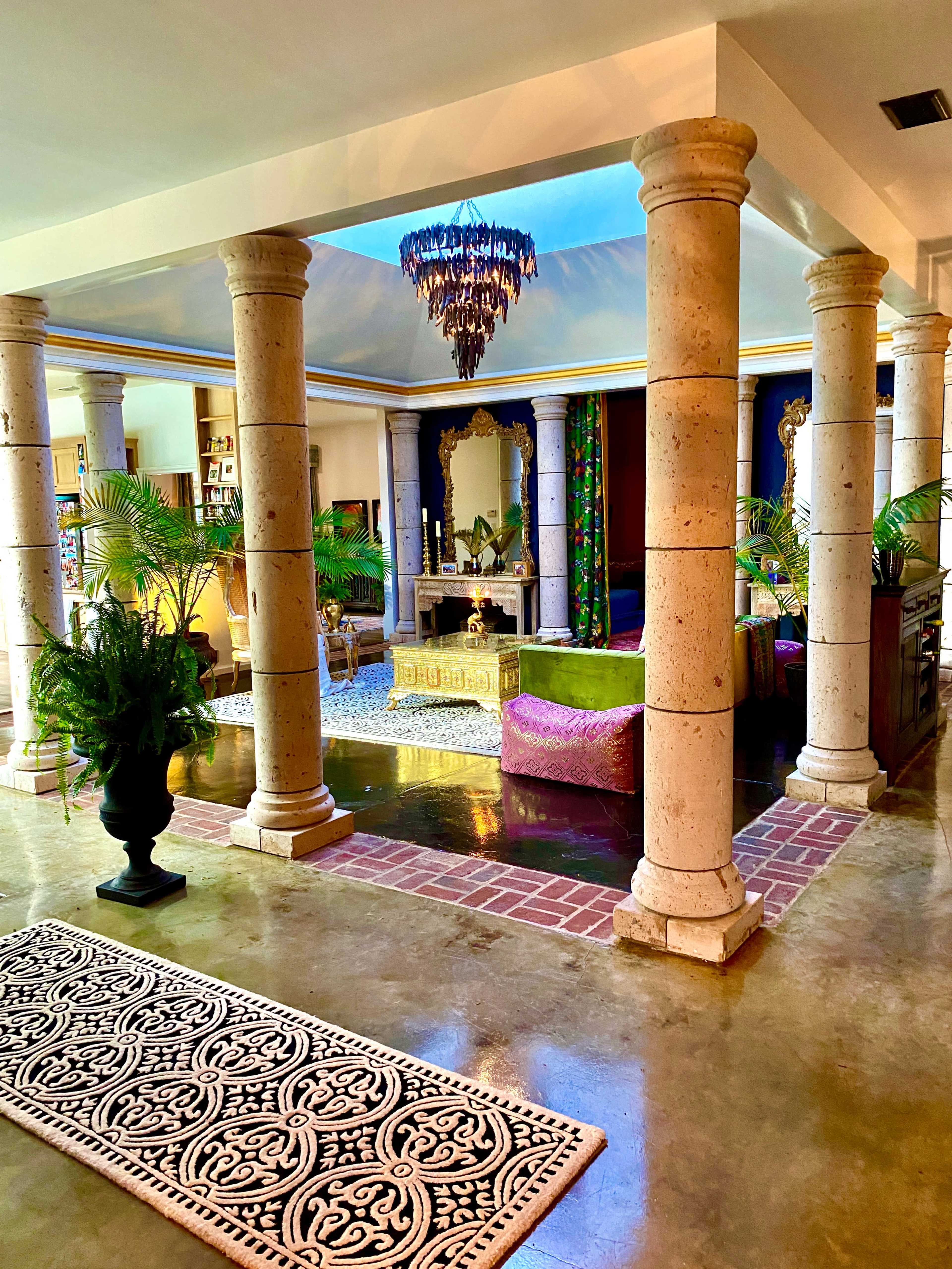 The interior features columns supporting a ceiling, with a vibrant seating area and decorative elements creating an open, inviting space.