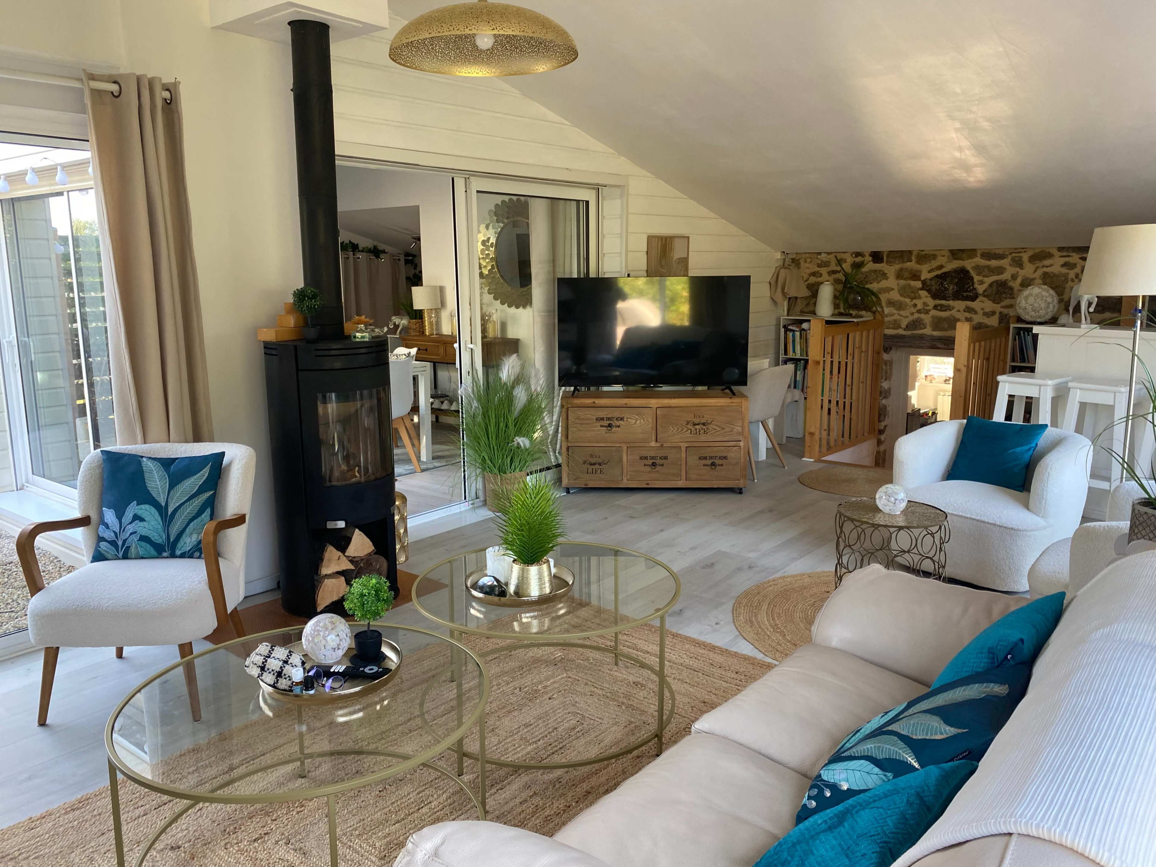 The living room features a light-colored sofa with decorative cushions, a round coffee table, a fireplace, and large windows allowing natural light.