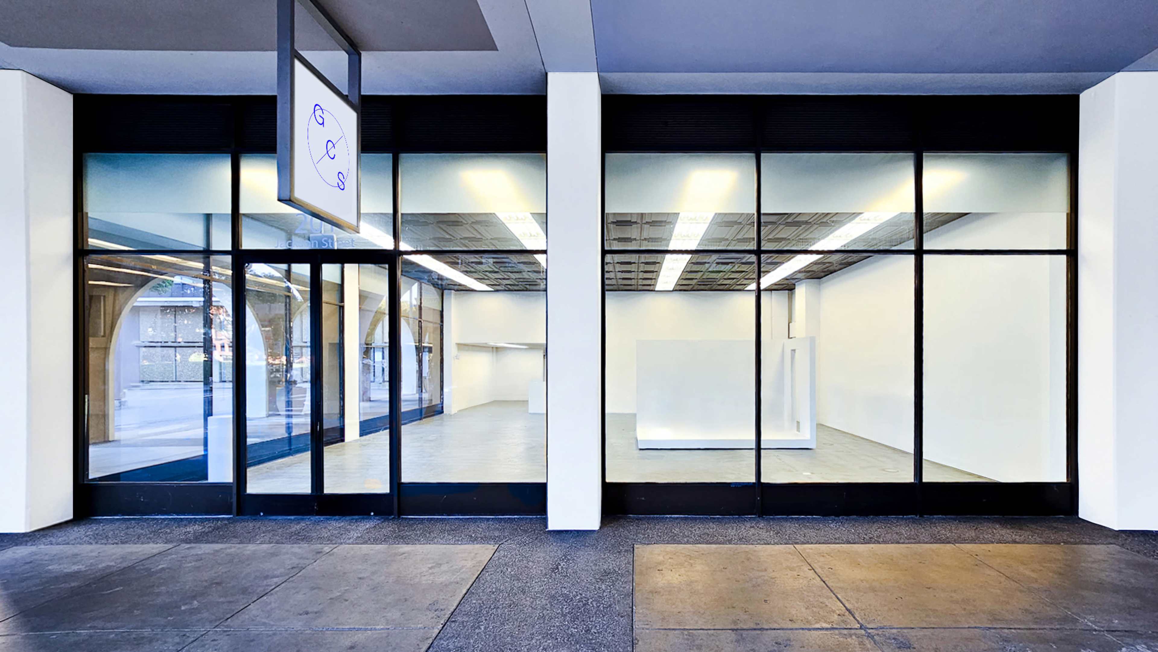 The image shows a storefront with large glass windows displaying an empty interior space.