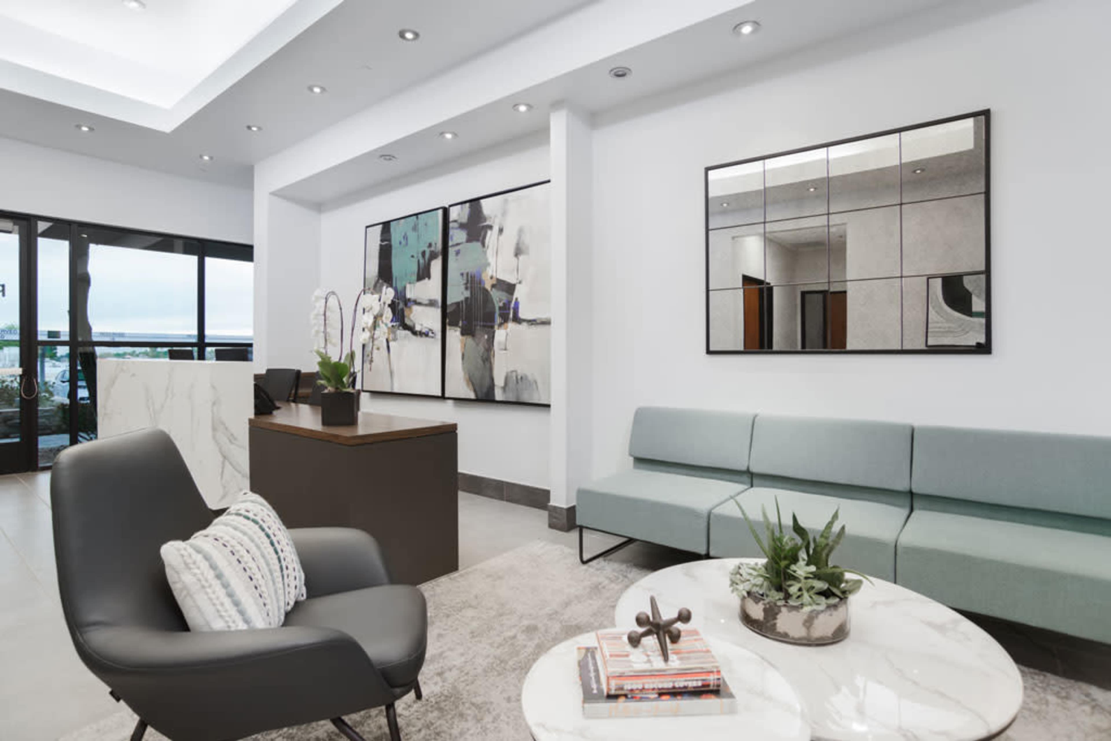 A modern lobby area with a light-colored sofa, a round coffee table, and large abstract art pieces on the walls.