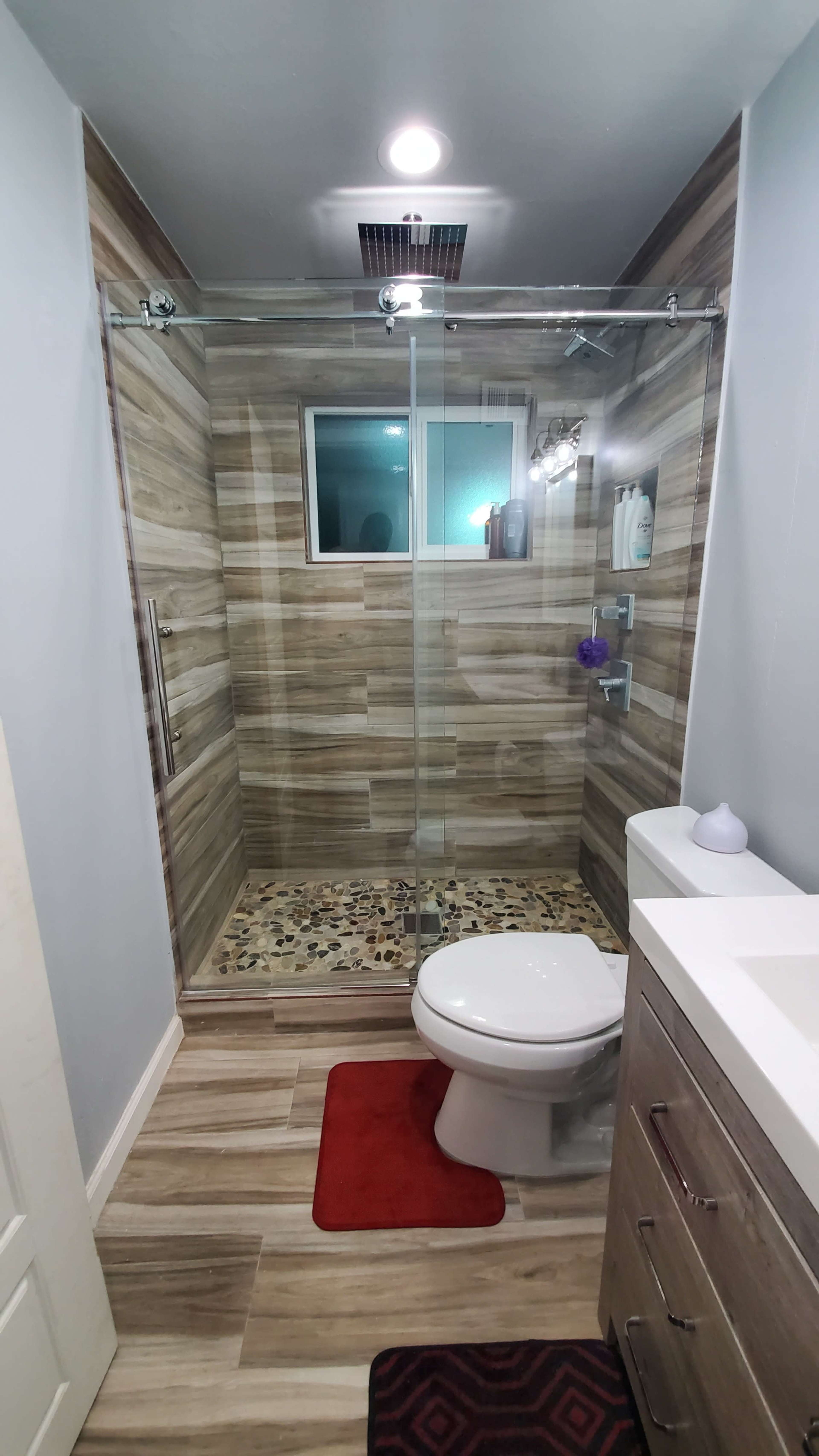 A modern bathroom featuring a glass shower enclosure, a toilet, and a vanity with a sink.