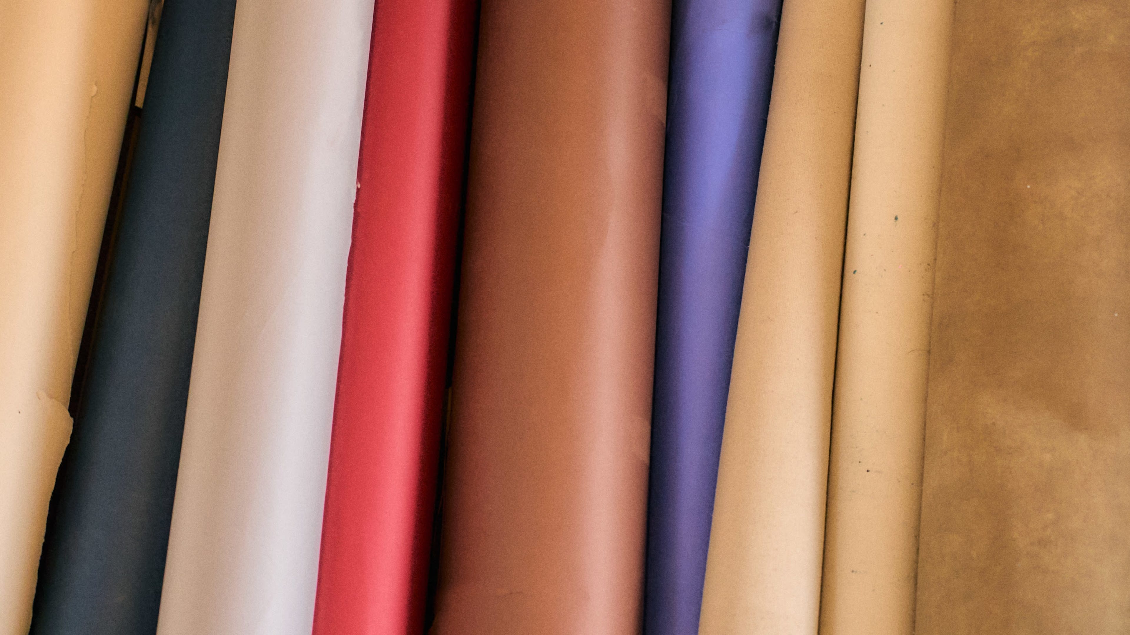 The image shows a collection of rolled sheets of various colored paper stacked vertically.