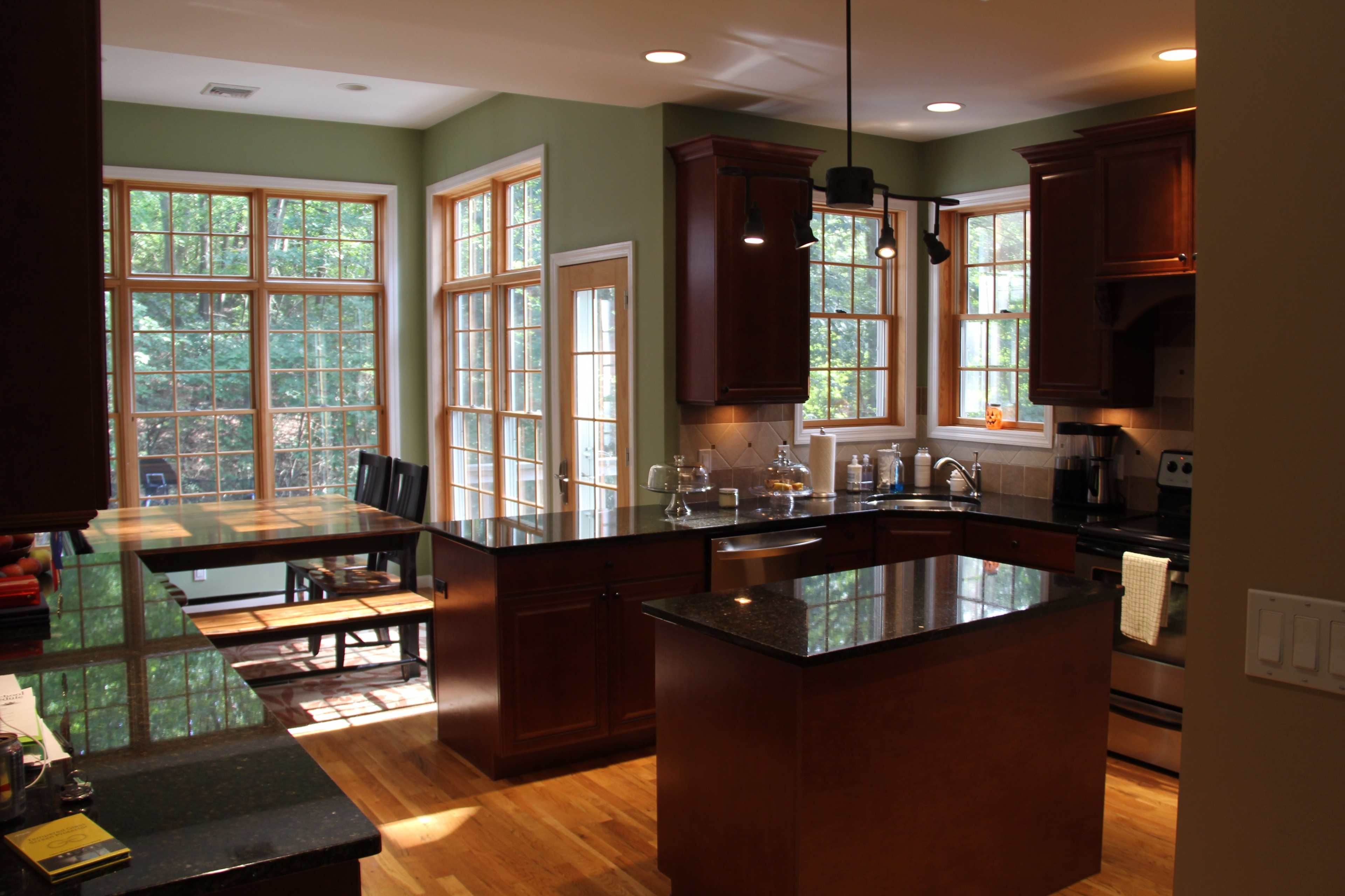 A kitchen with dark wood cabinets, stainless steel appliances, and large windows allowing natural light.