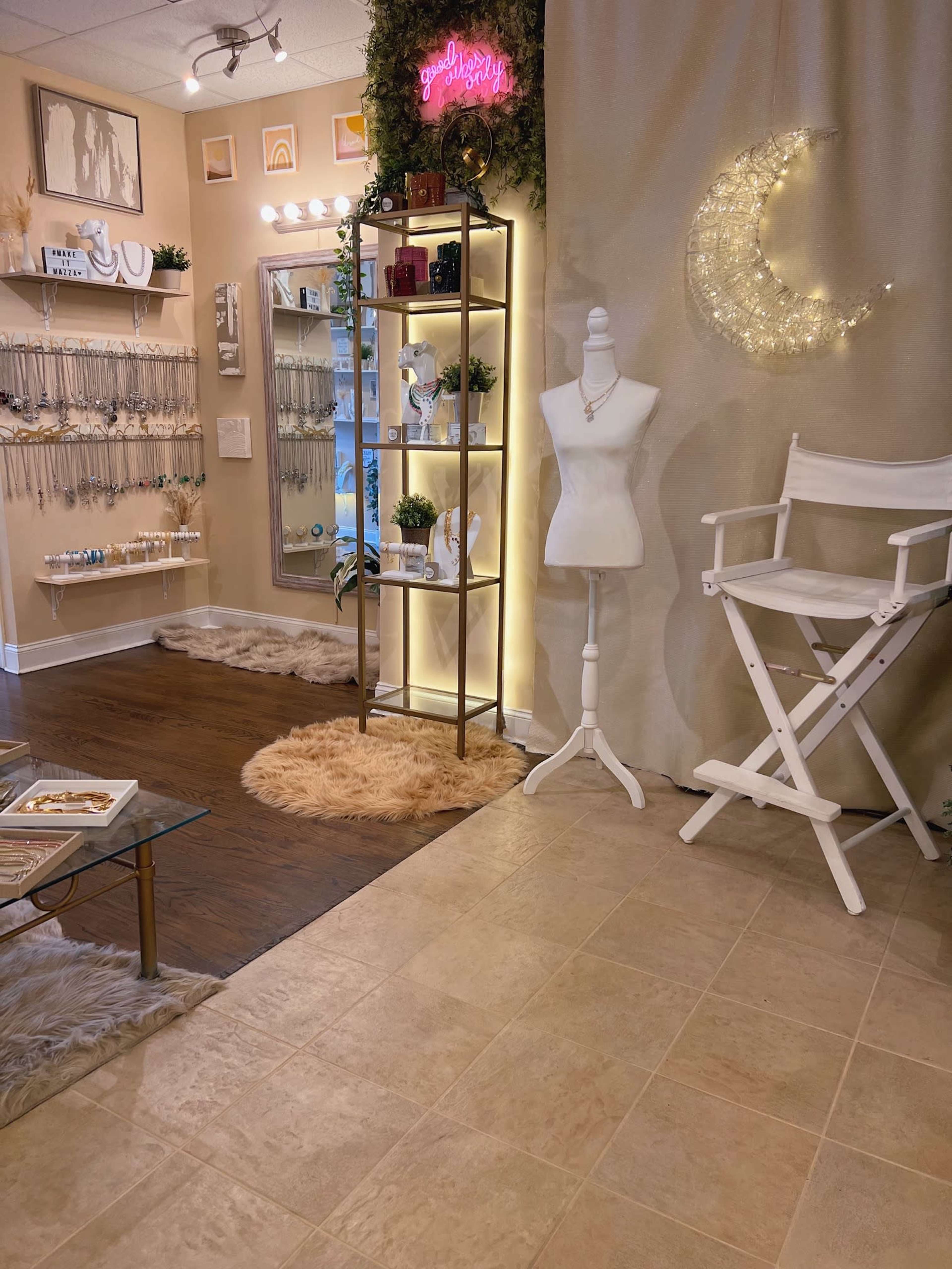 A boutique interior featuring a display shelf, a mannequin, a director's chair, and soft, decorative lighting against a neutral backdrop.
