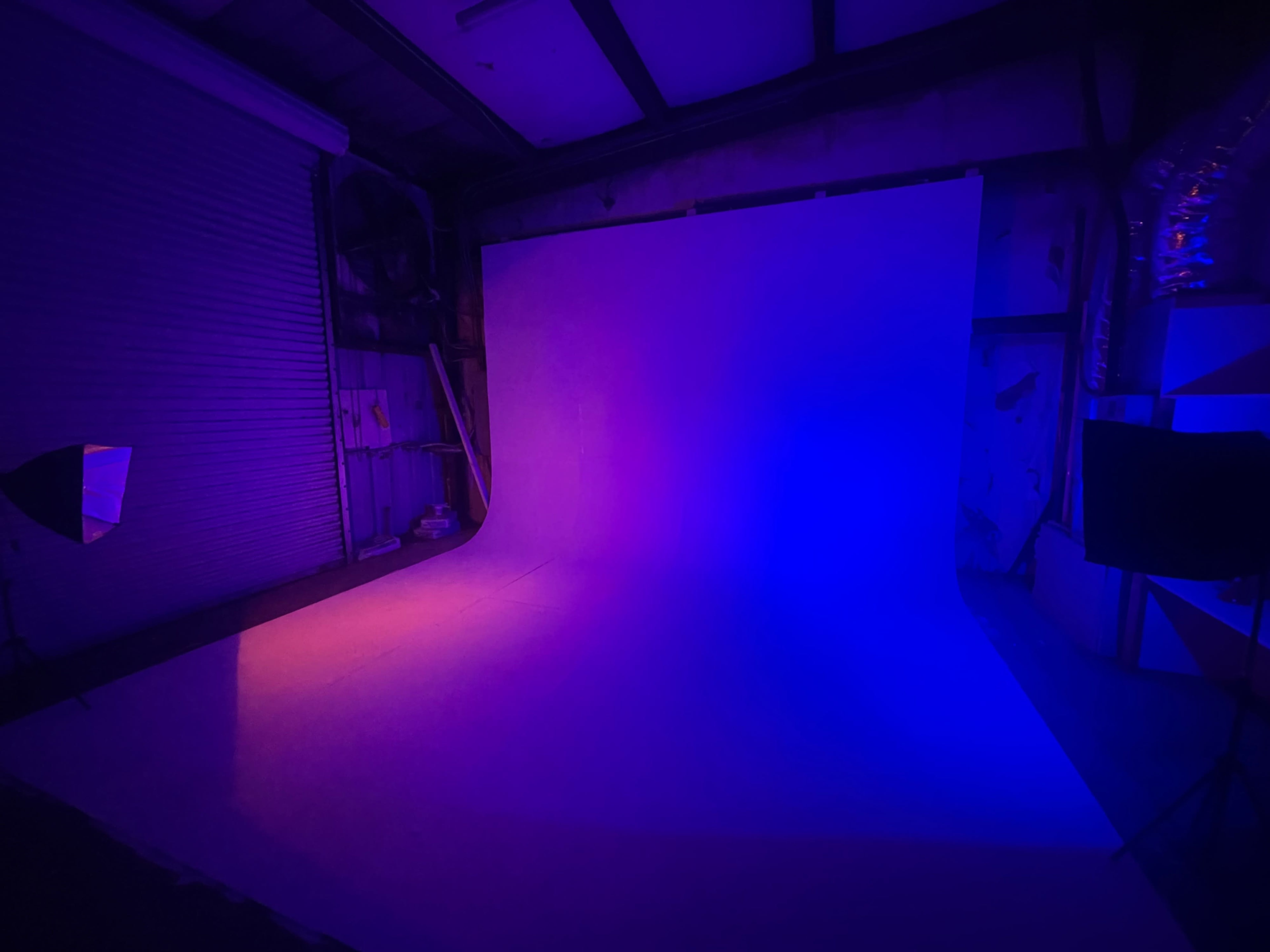 A photography studio with a curved backdrop illuminated in purple and orange light.