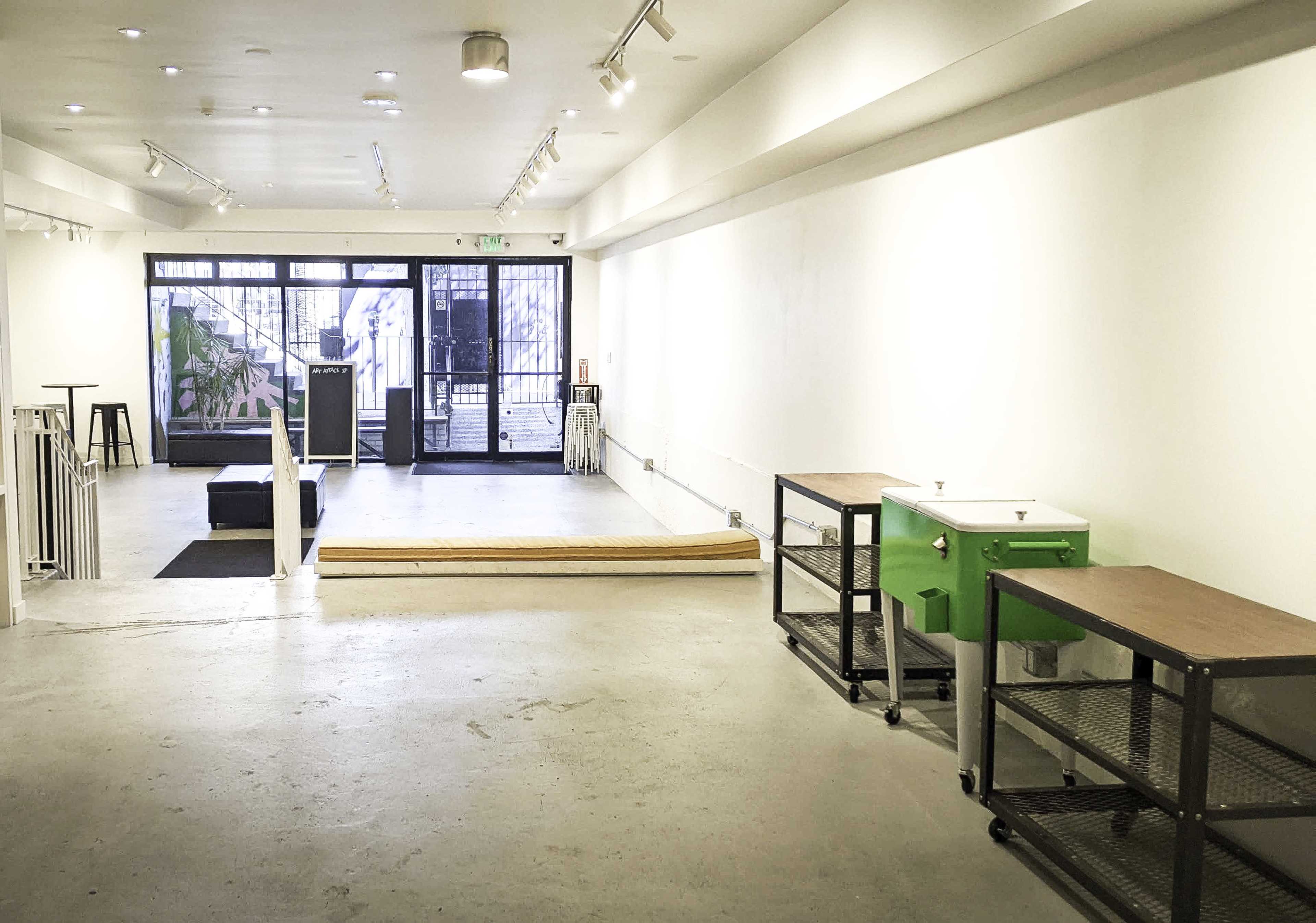 An empty, well-lit interior space with concrete floors, wooden steps, and two carts near a large glass entrance.