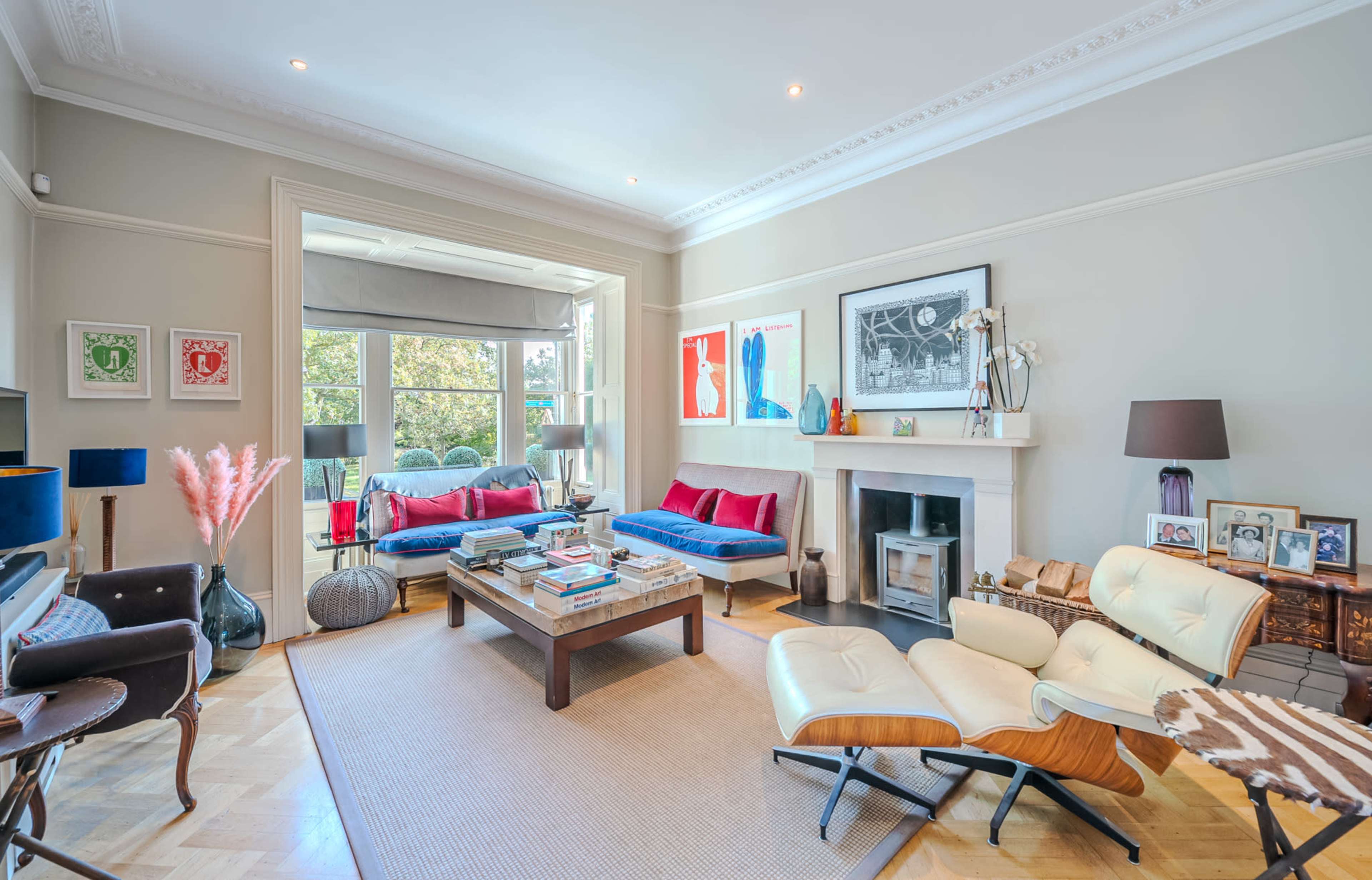 A living room with a fireplace, a large coffee table, seating areas with bright cushions, and a view of a balcony.