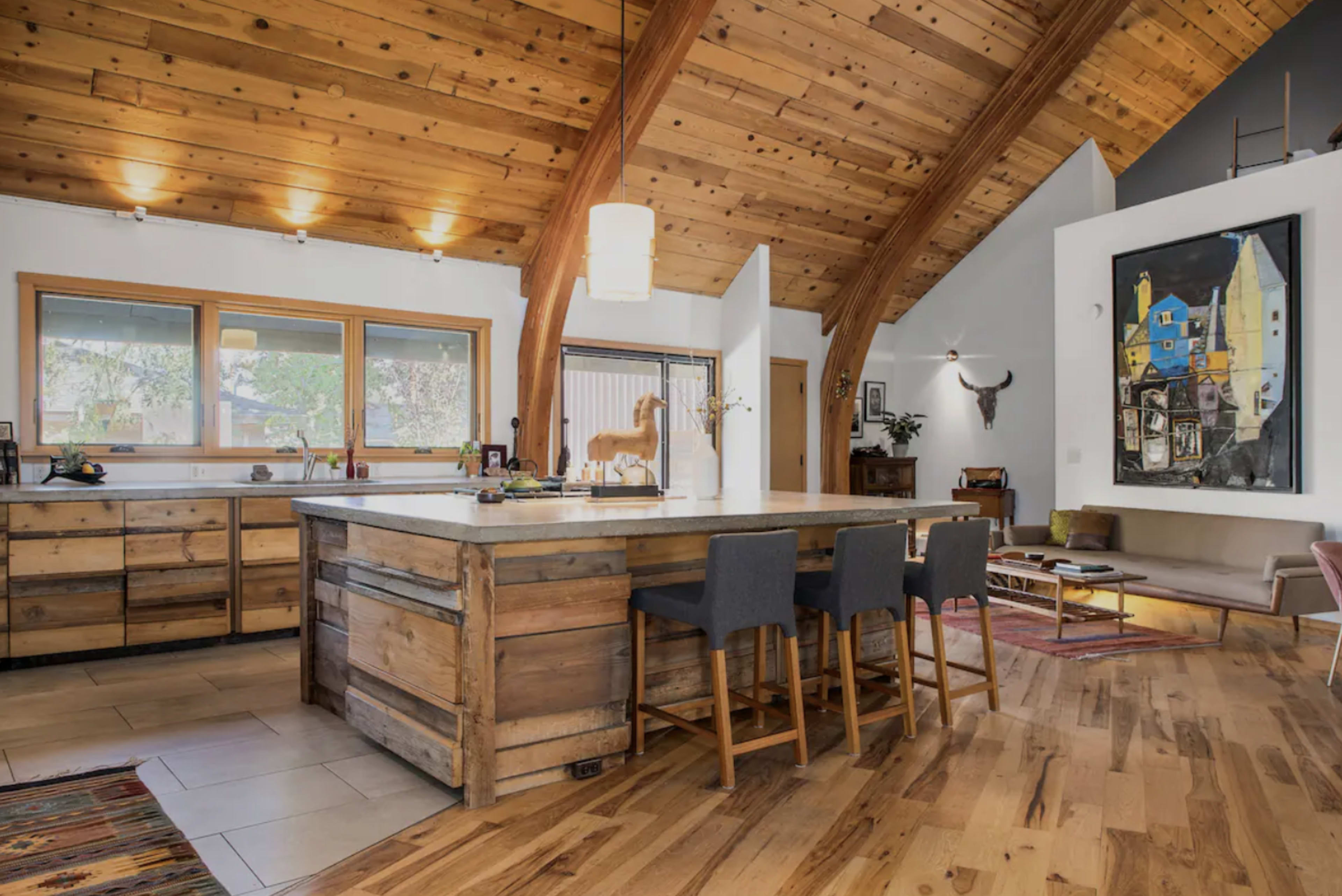 A modern kitchen with an island, wooden beams, and a combination of rustic and contemporary design elements.