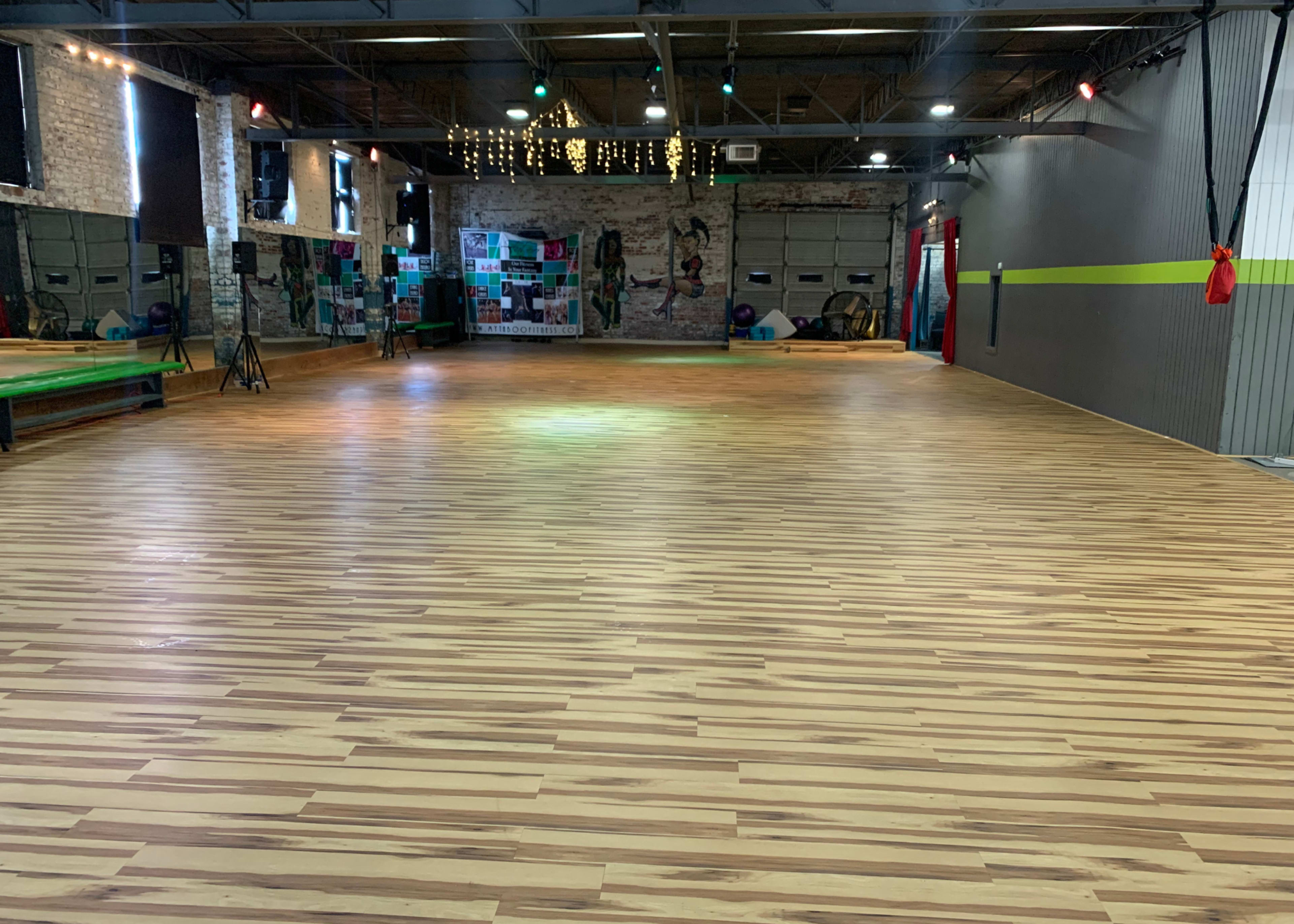 A spacious, wooden-floored gymnasium with mirrored walls and colorful decor.