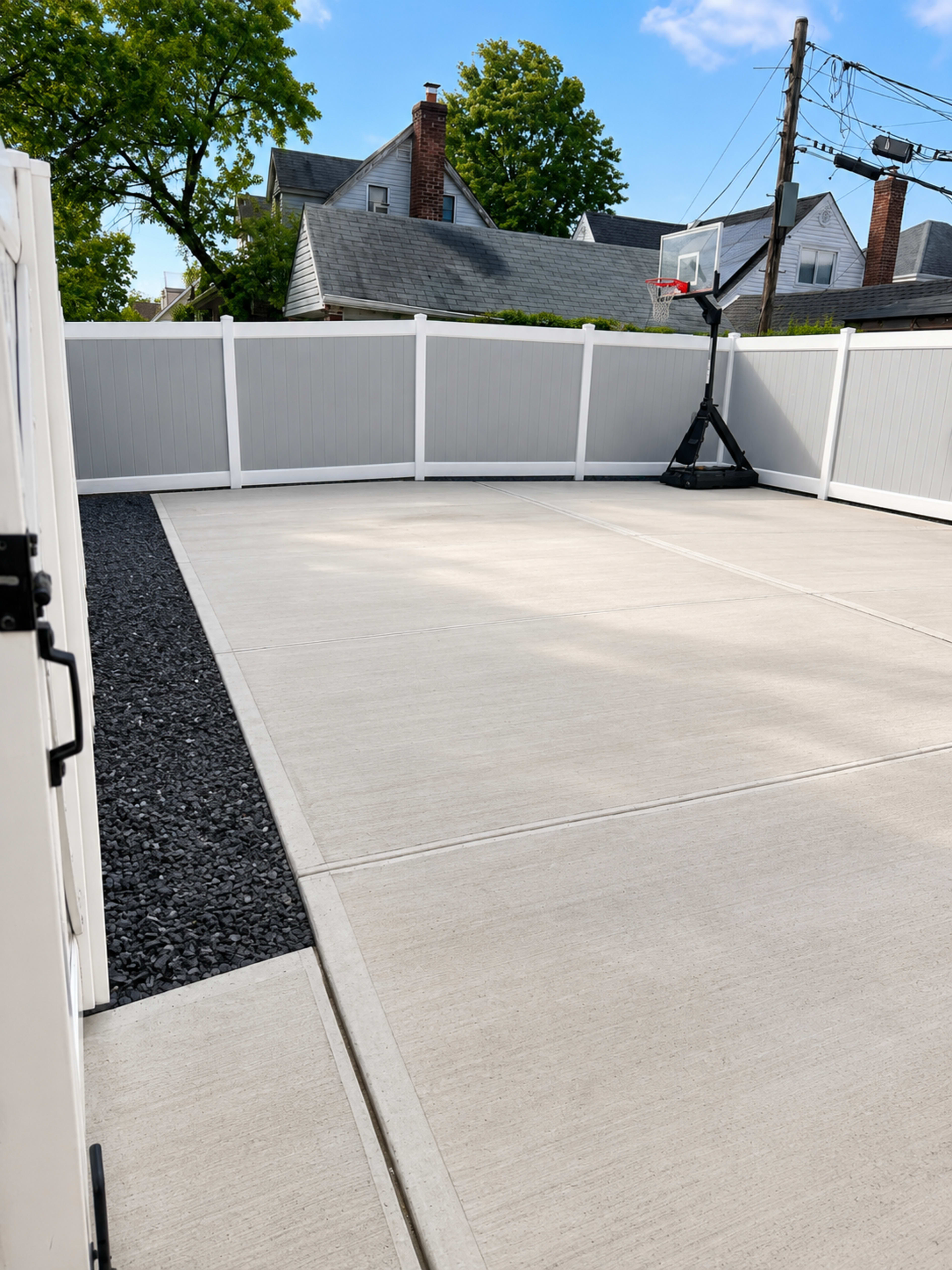 The image shows a fenced outdoor area with a concrete surface and a basketball hoop in the corner.