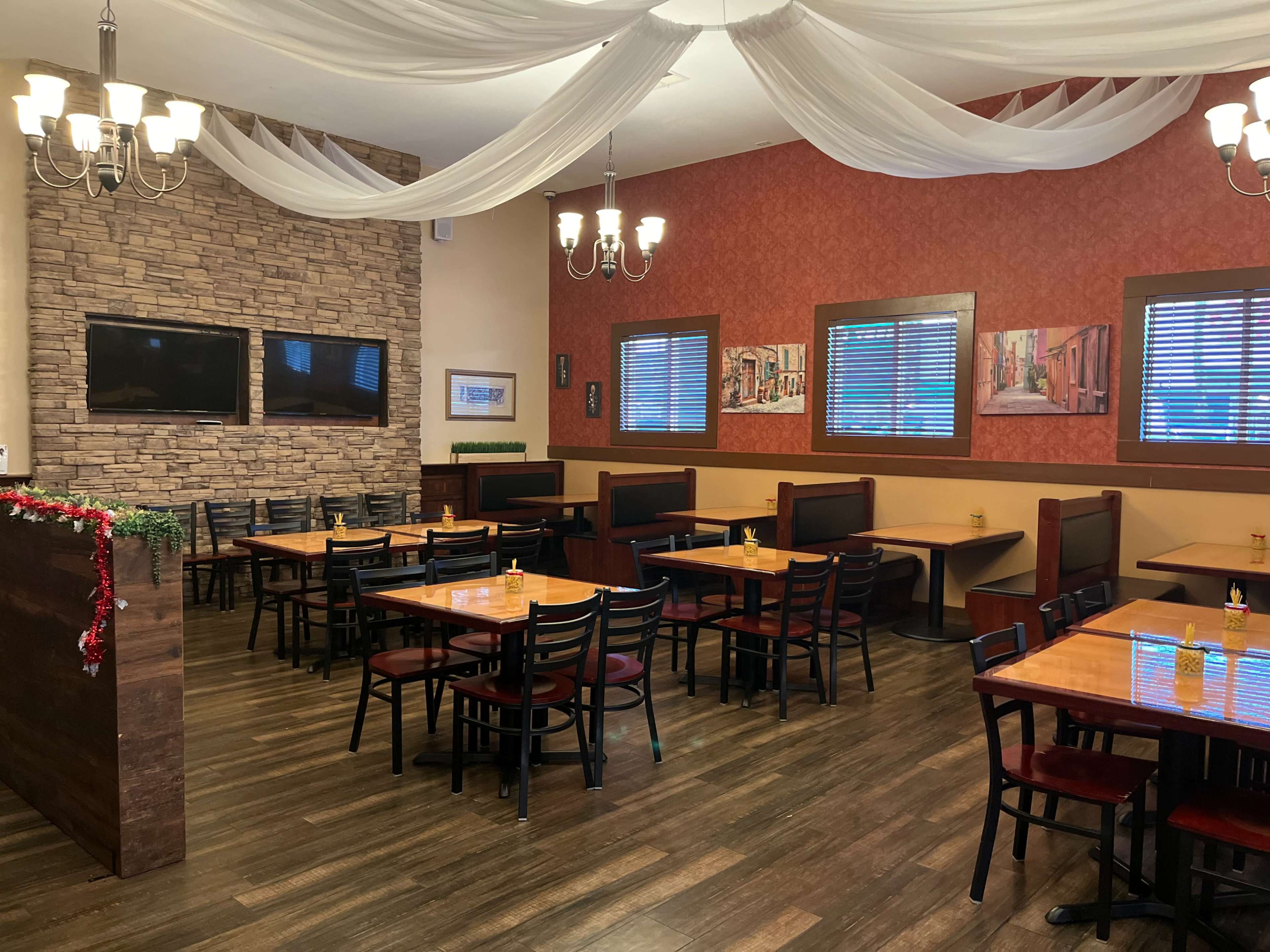 A restaurant interior featuring brown wooden tables and black chairs, with decorative wall panels and a stone accent wall.