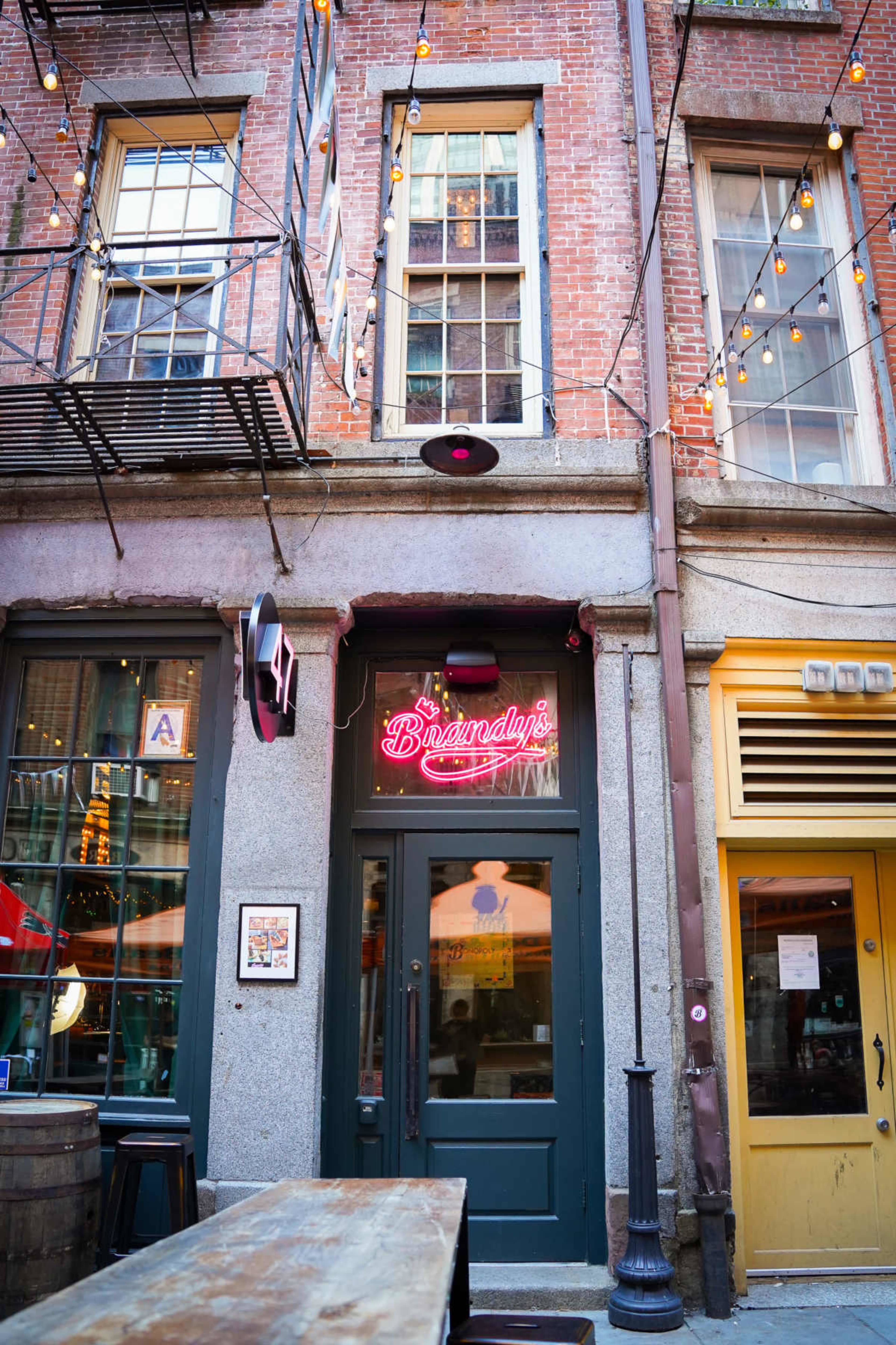 The image shows the entrance of a restaurant named "Bannaly's," framed by brick walls and illuminated by string lights.