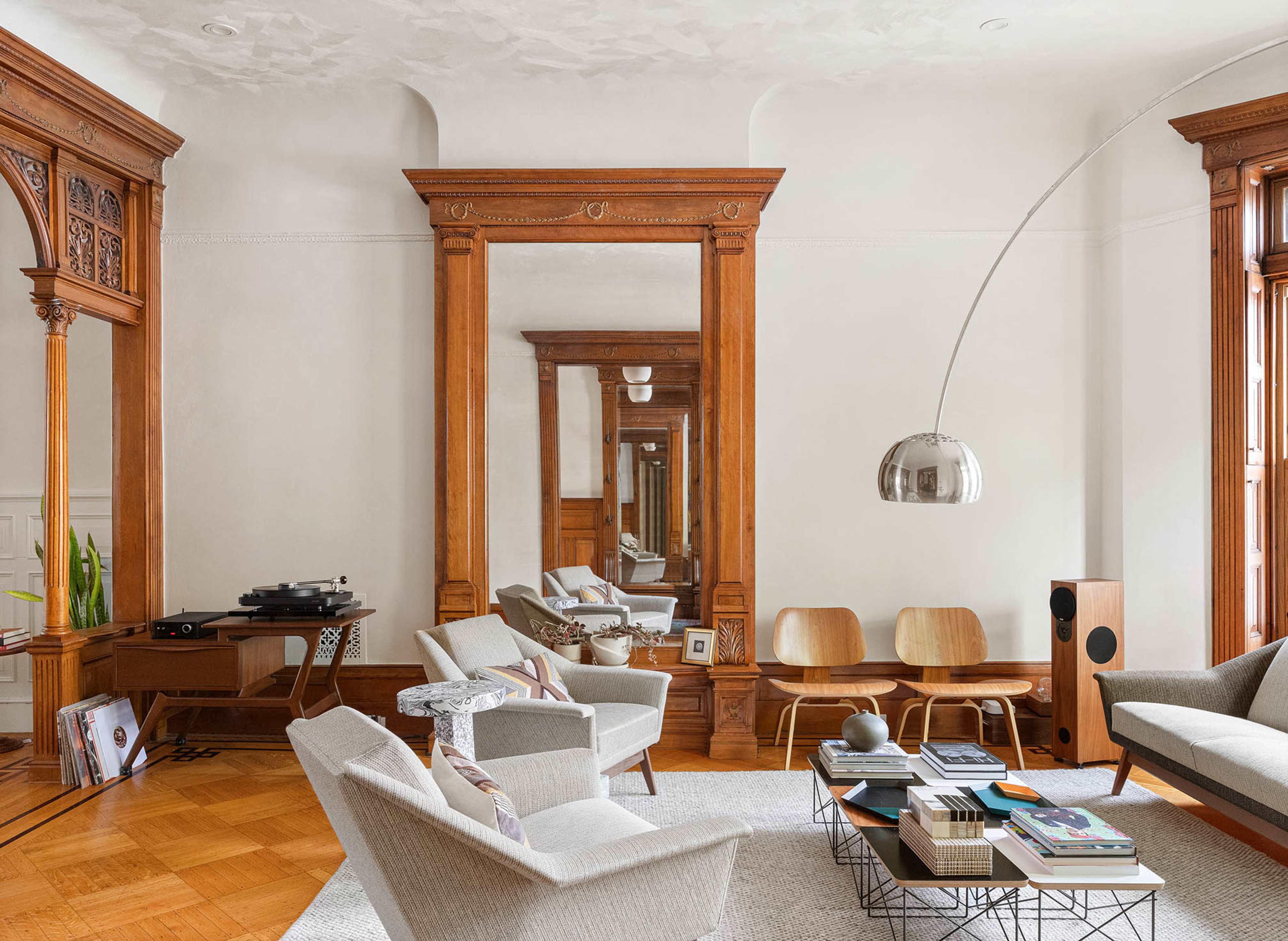 A spacious living room features a large mirror, wood accents, modern furniture, and a record player.