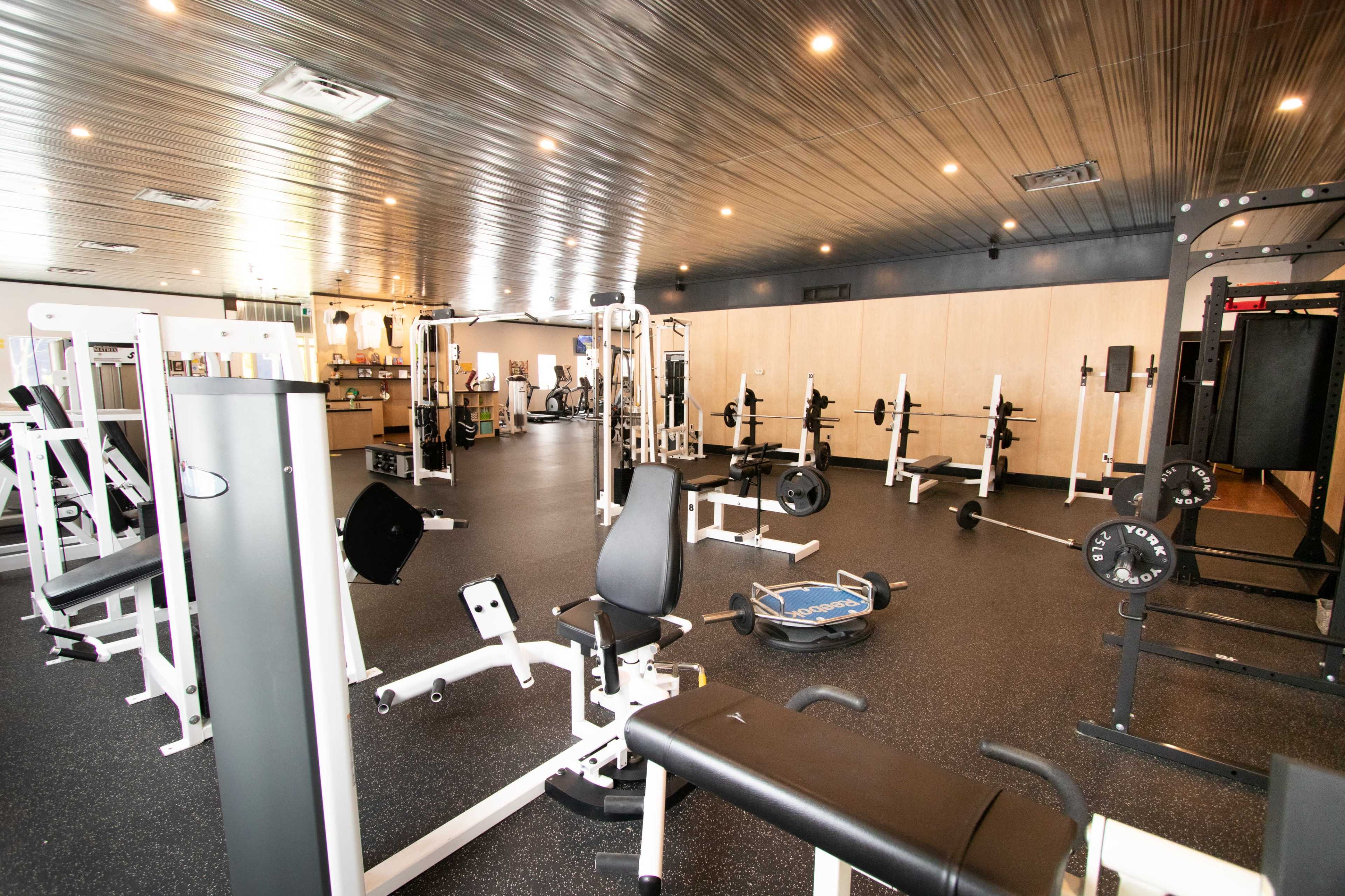 A spacious gym filled with various weightlifting equipment and exercise machines on a rubberized floor.