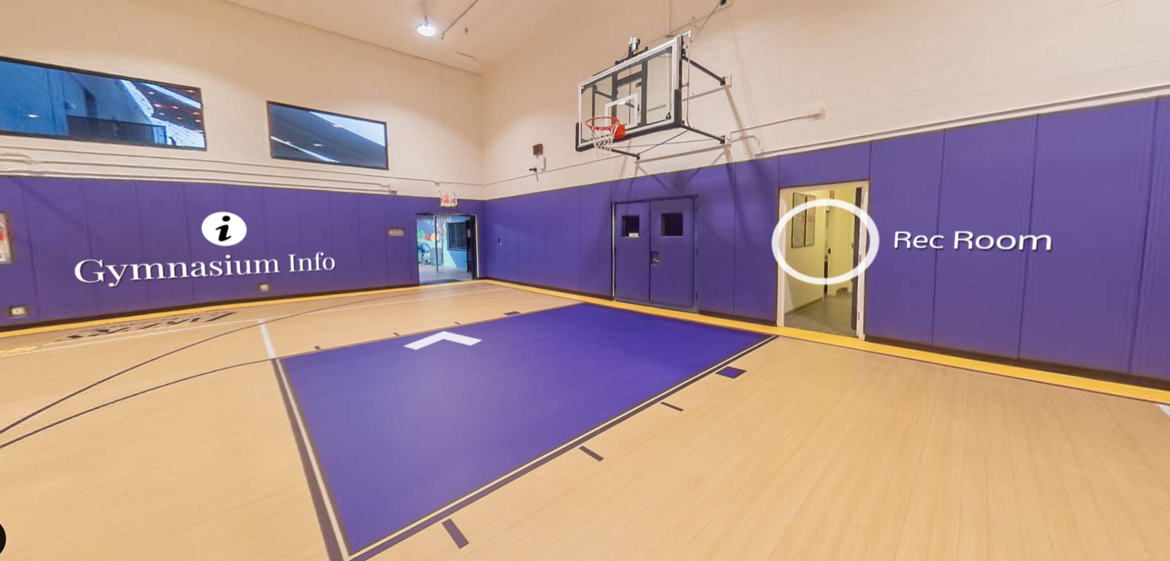 A gymnasium interior with a basketball hoop and a doorway leading to a rec room.