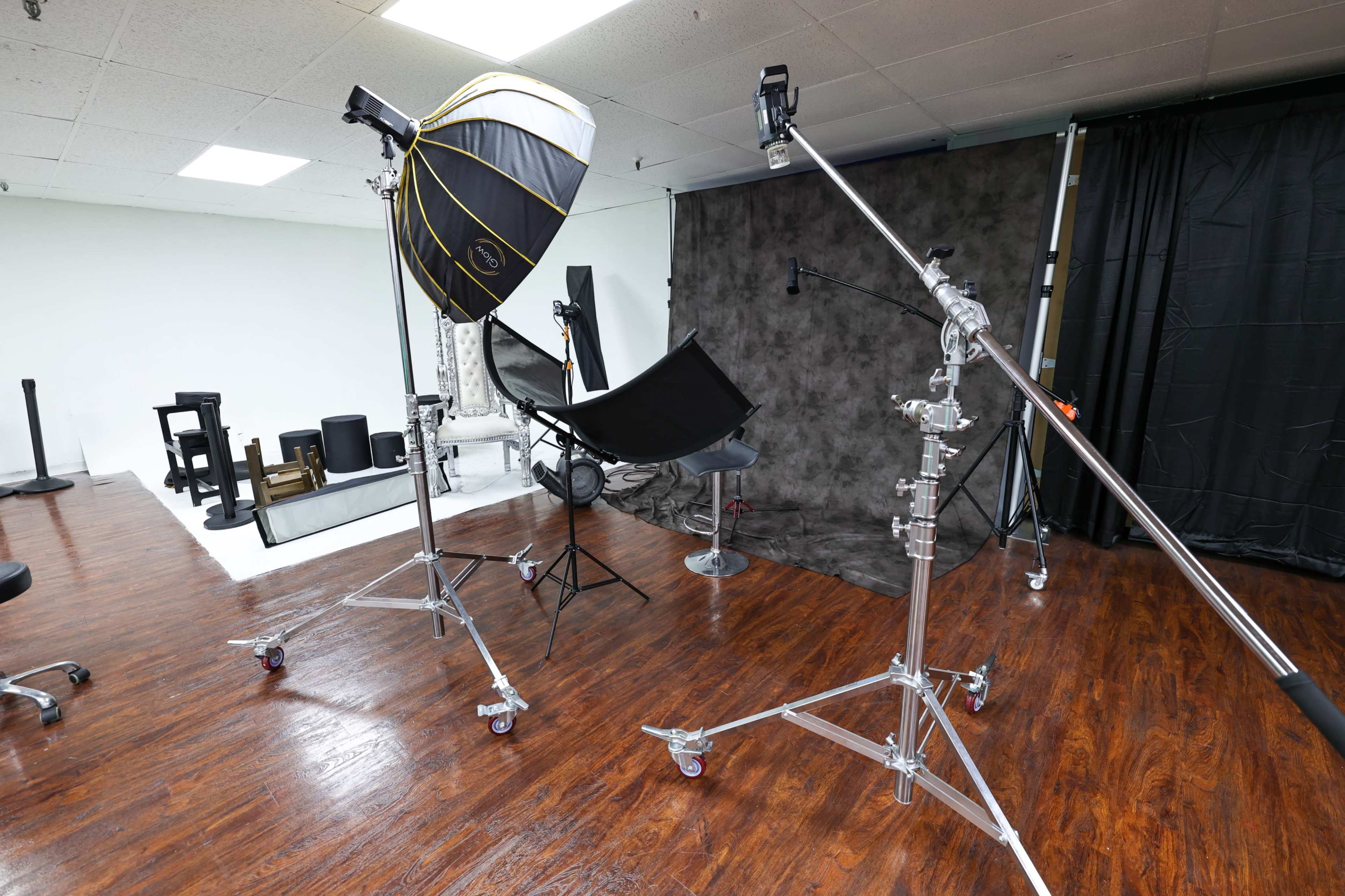 A photography studio setup with various lighting equipment and props arranged in a spacious area.