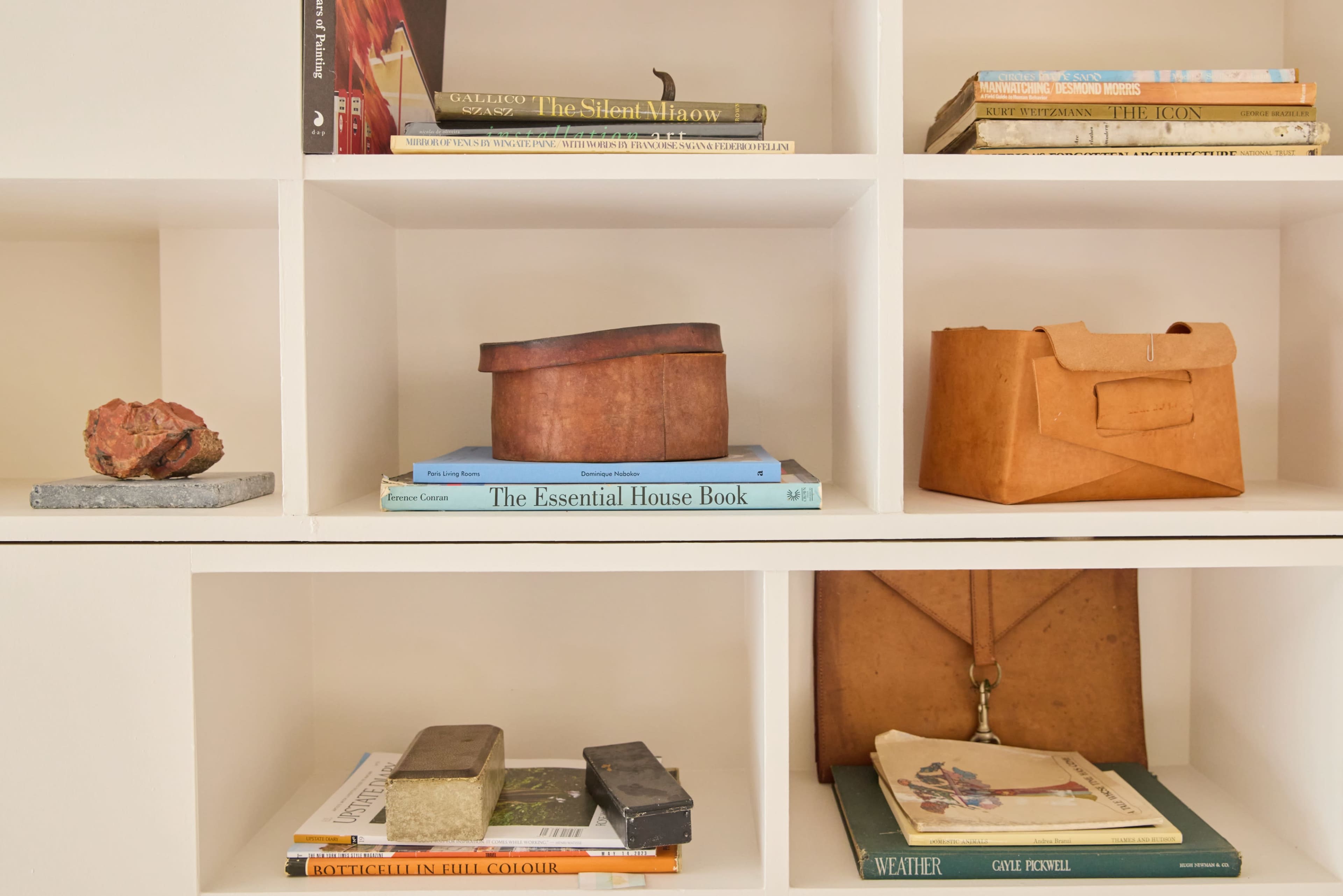 The image shows a series of shelves filled with books, decorative boxes, and various objects.