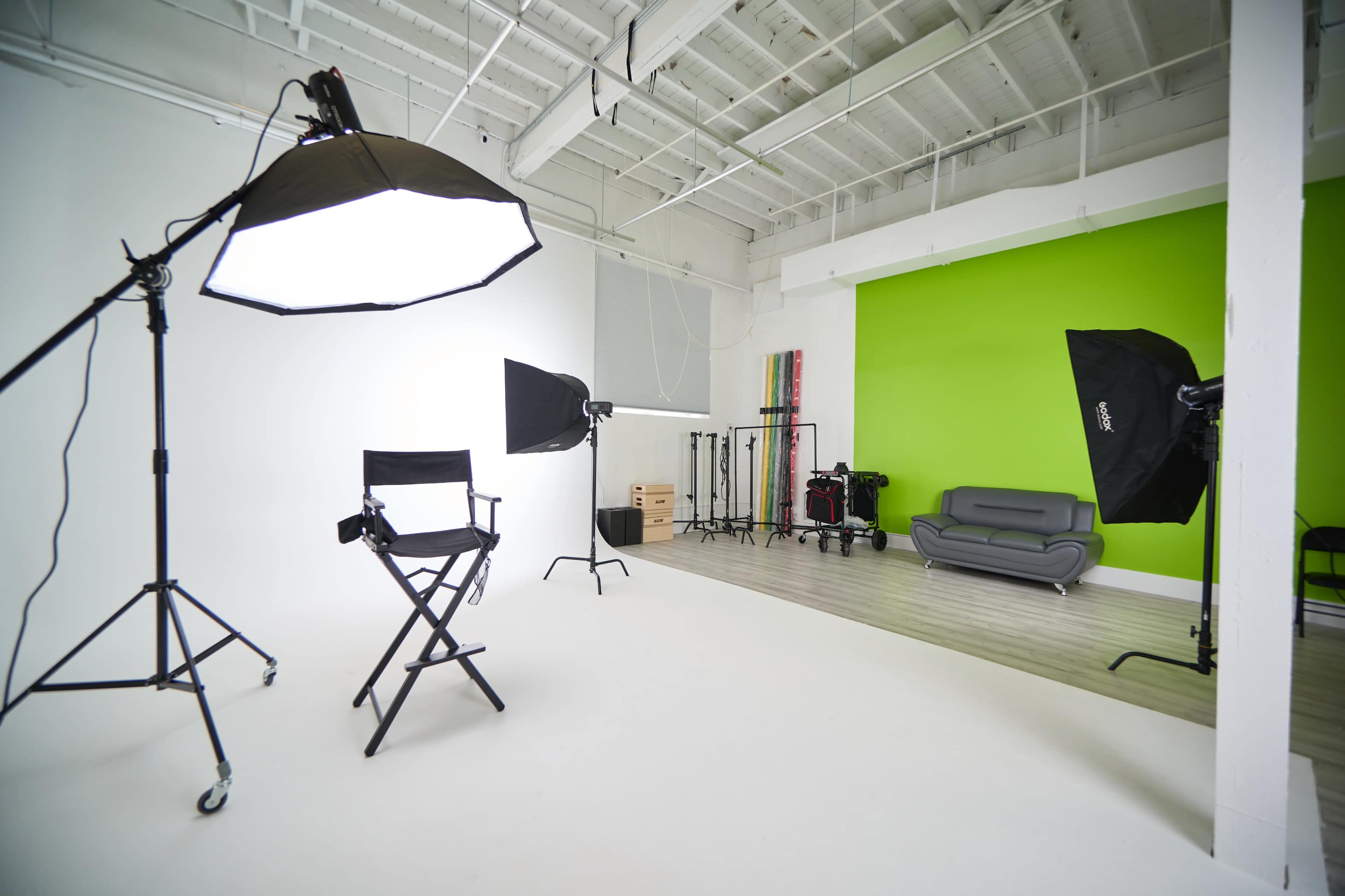 A photography studio with softbox lights, a director's chair, and a green accent wall.