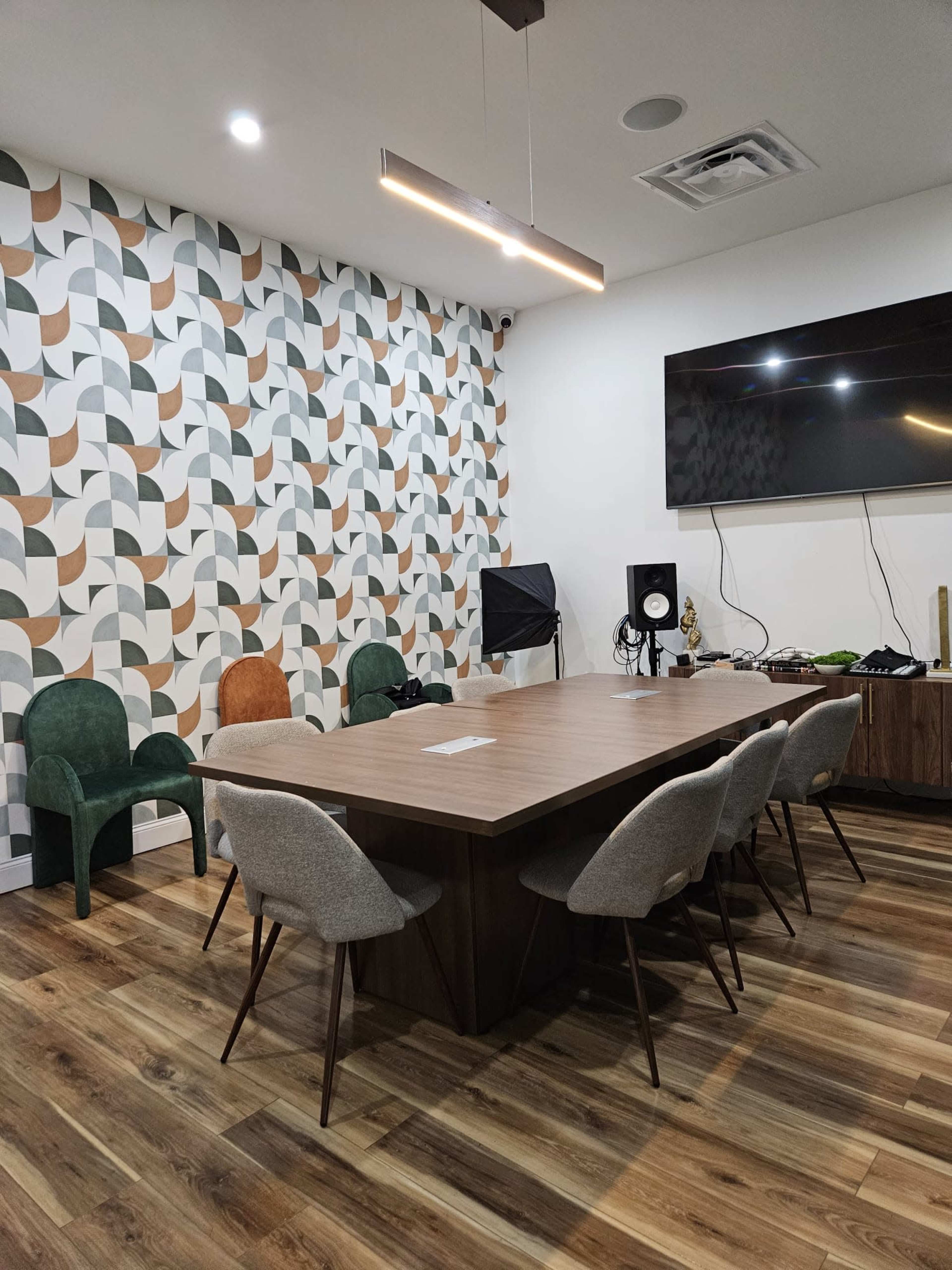 A modern conference room with a large table surrounded by several chairs and a decorative wall featuring geometric patterns.