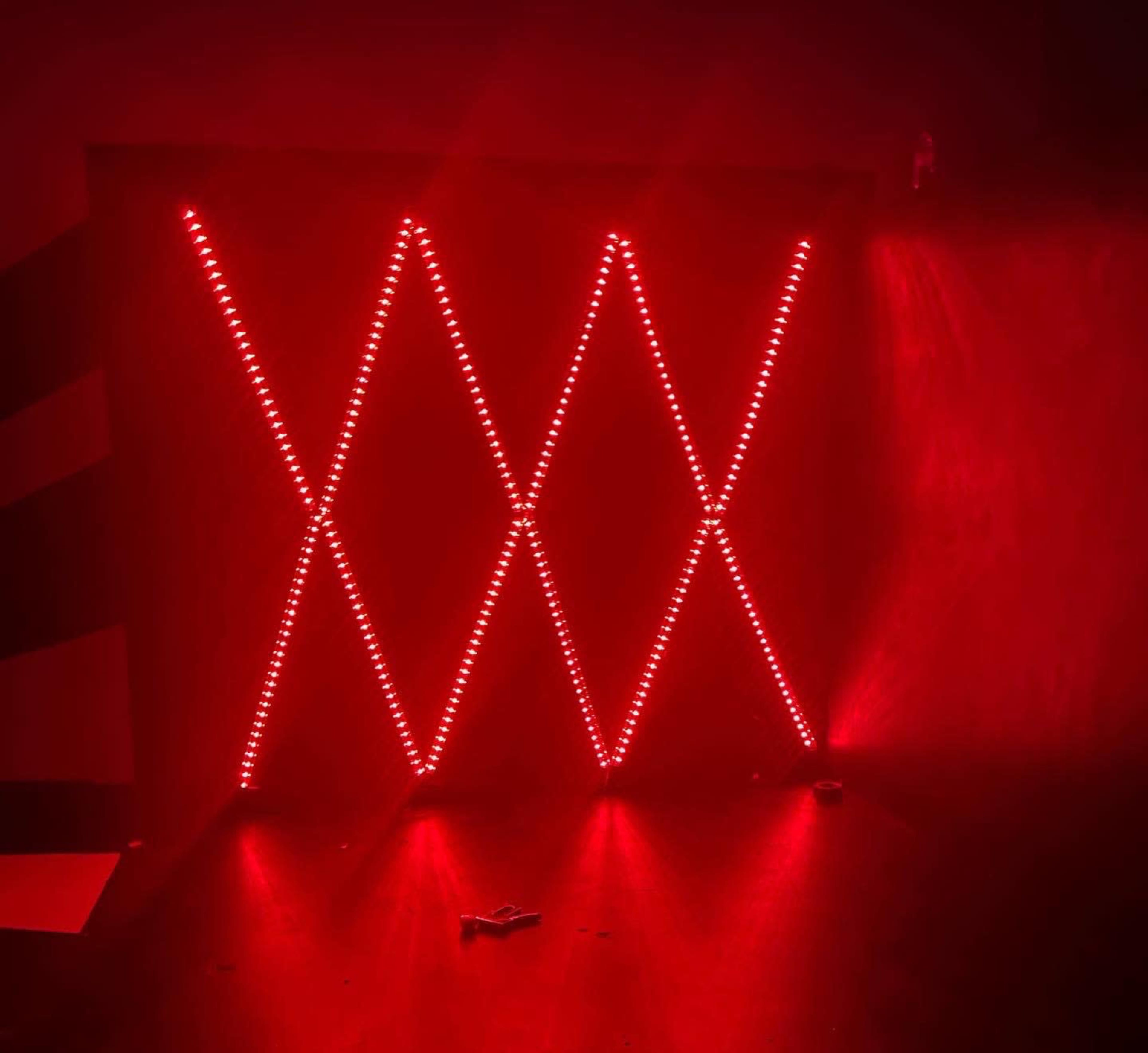 A wall display of LED lights arranged in a crisscross pattern, emitting a red glow.