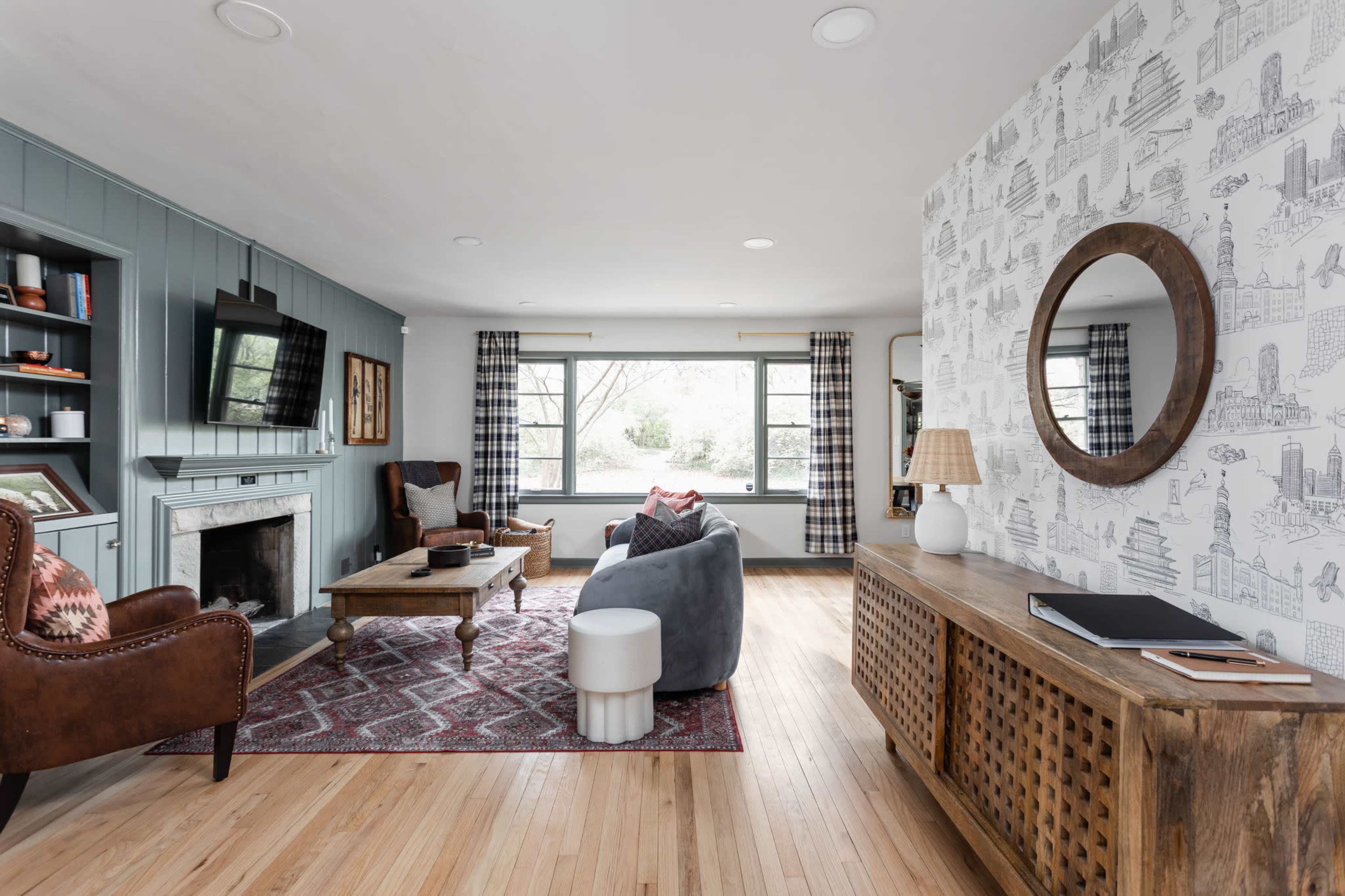 A living room with a seating area, a coffee table, and decorative elements against a backdrop of large windows and a patterned wall.