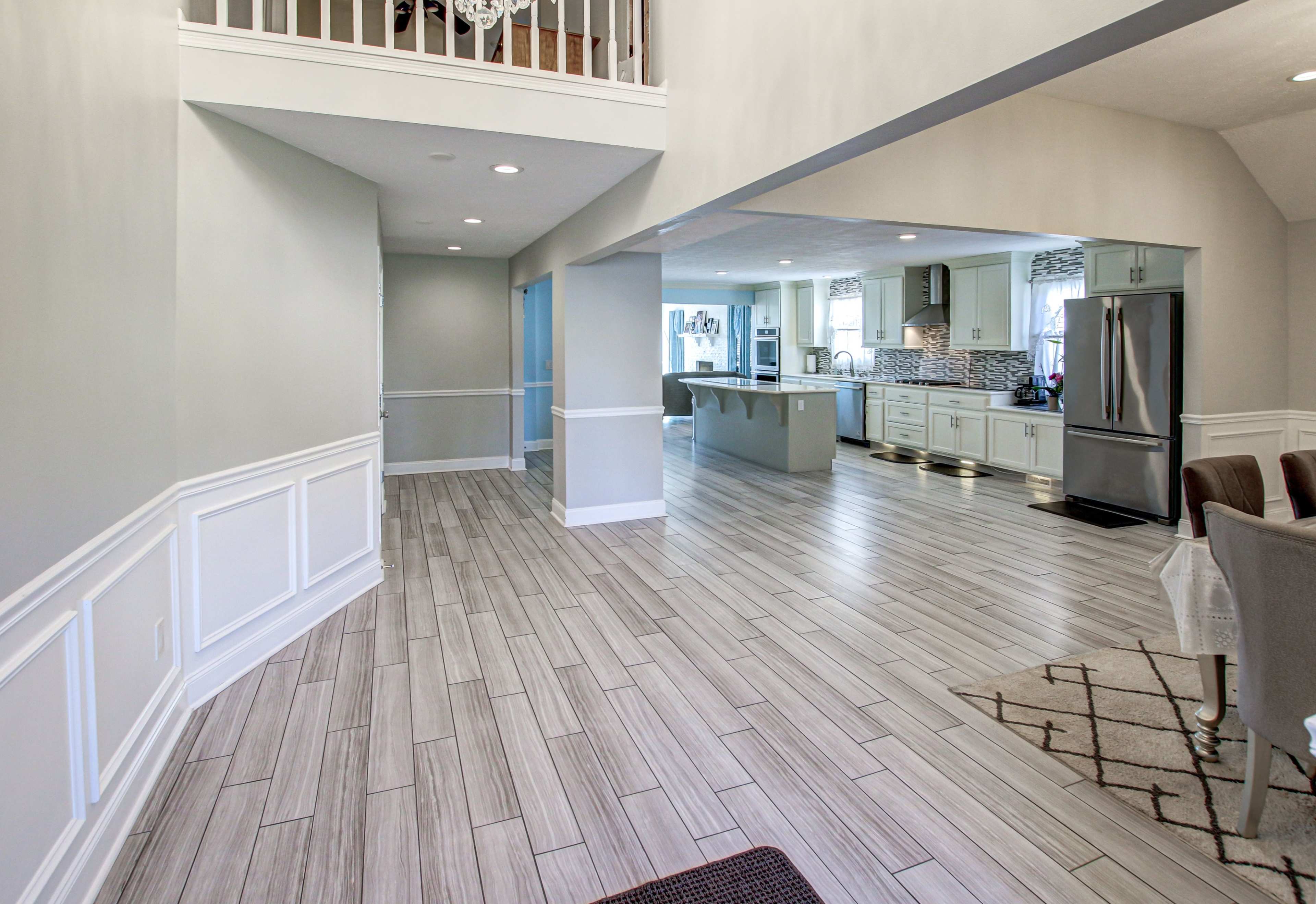 A spacious open-concept living area with tile flooring, leading to a kitchen and dining area.